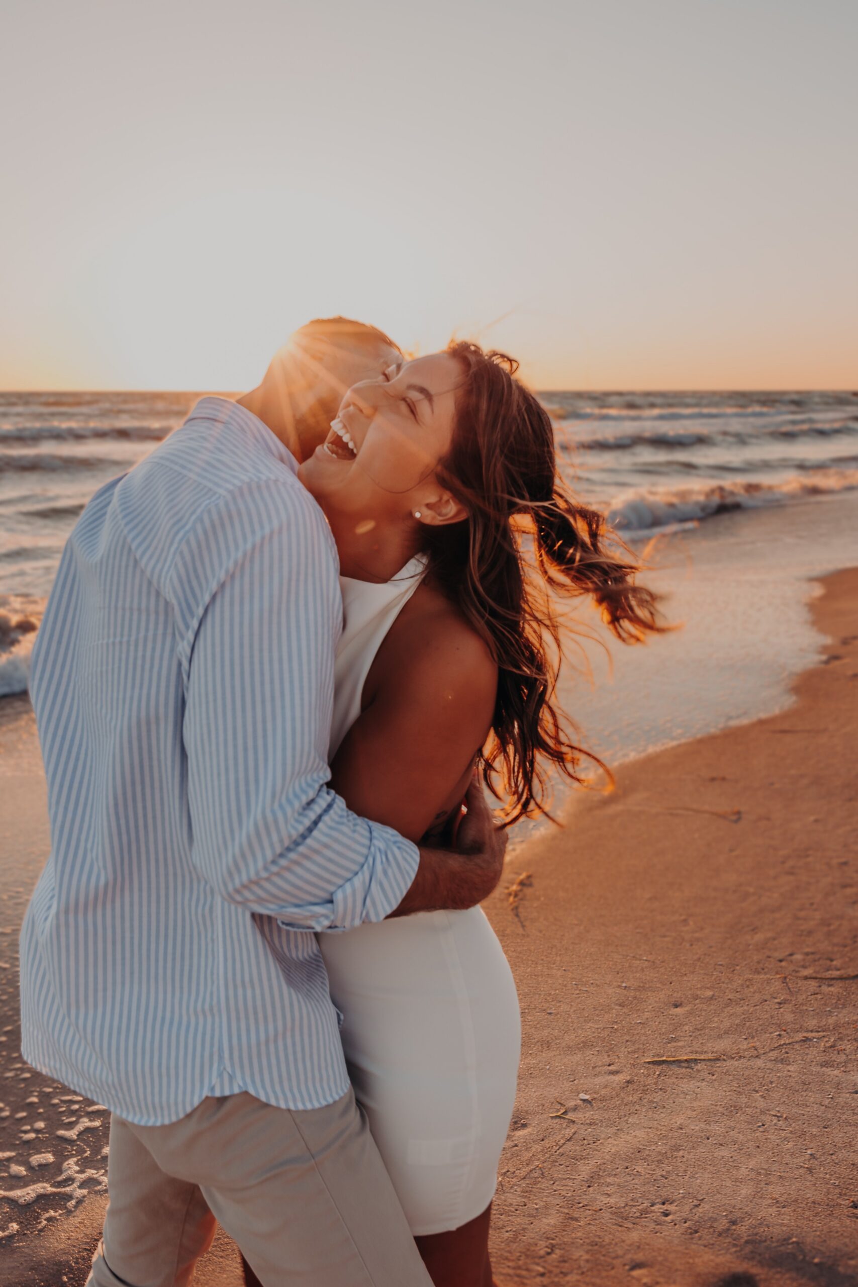 Bianca and Patrick laughing together during golden hour portraits on Longboat Key beach after their engagement, photographed by Angela Moon Photography Sarasota