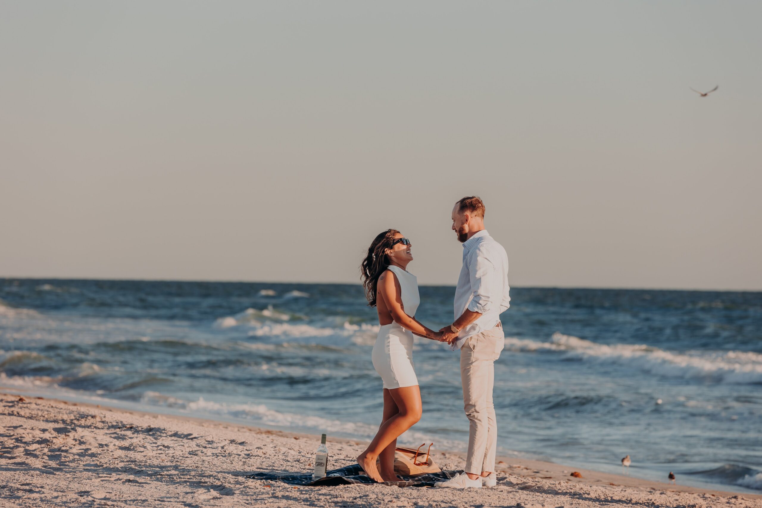 Bianca and Patrick standing on Longboat Key beach at golden hour just before the surprise beach proposal, photographed by Sarasota proposal photographer Angela Moon Photography