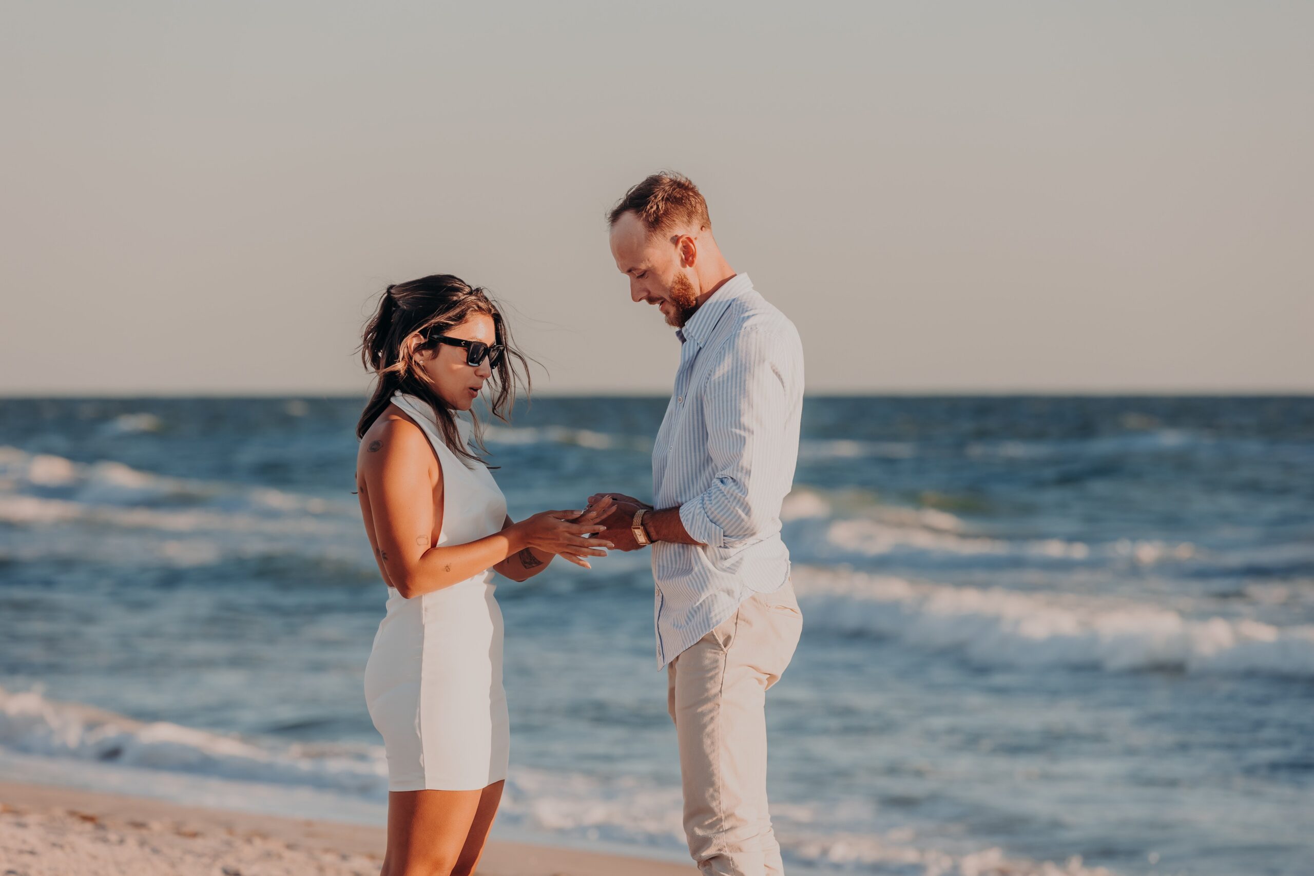 Bianca and Patrick laughing together on Longboat Key beach at golden hour after their engagement, natural and candid beach proposal portraits by Sarasota photographer Angela Moon