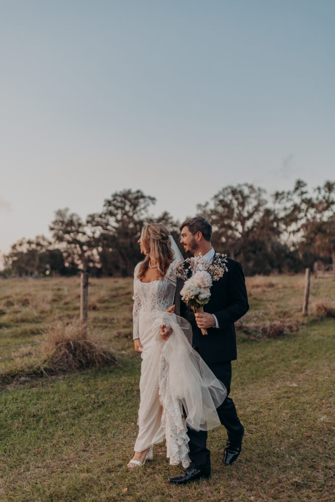 Couple walking hand in hand through tree-lined path at The Retreat Sarasota wedding.
