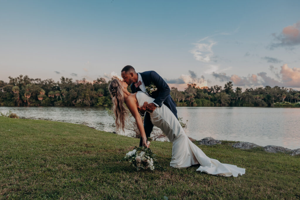 bride and groom dip during sunset portraits with views of the lake at the worthington for events wedding