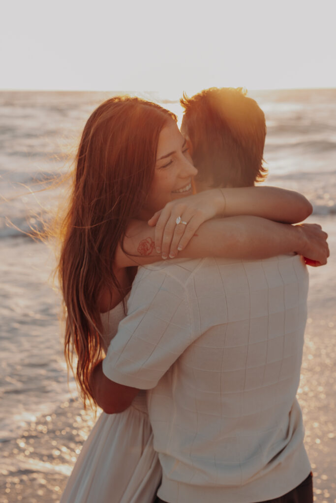 Engaged couple celebrating on Siesta Key beach at golden hour in Sarasota