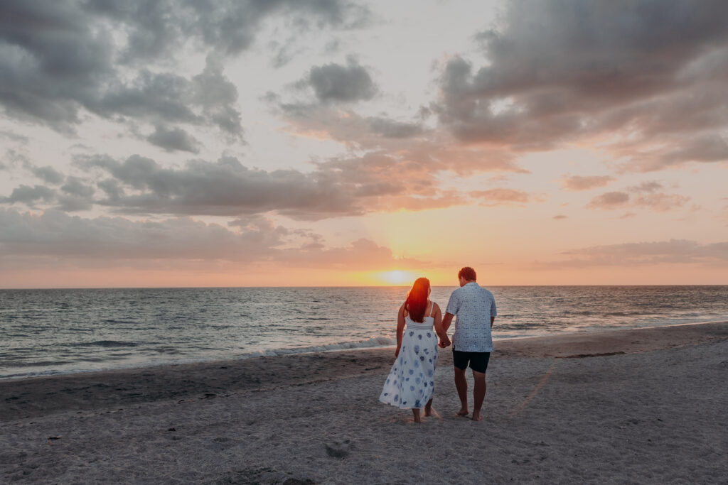 Couple walking on Longboat Key beach at sunset after proposal Sarasota Florida
