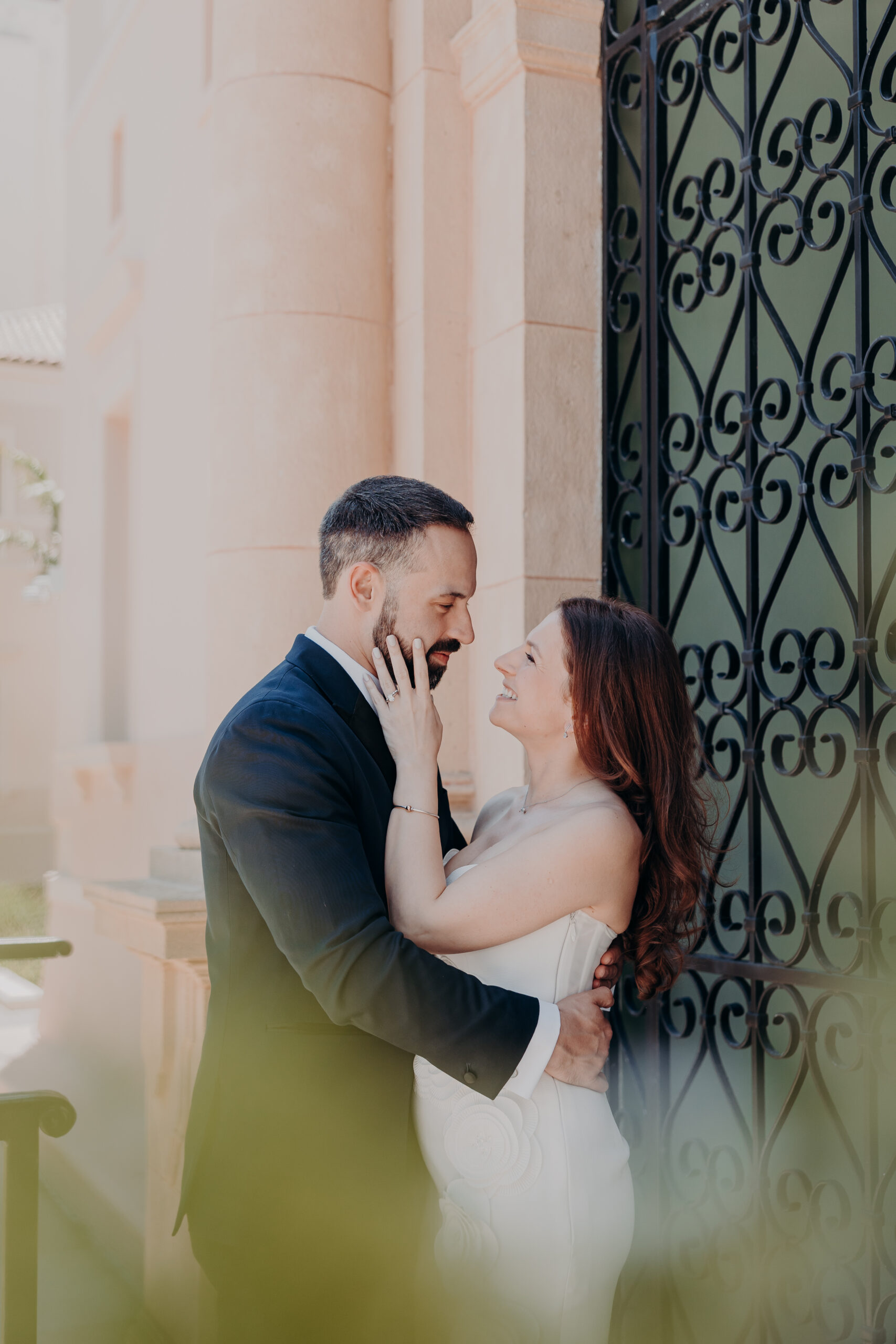 Diana touching Roberts face and smiling up at him beside the ornate iron gates at the Historic Sarasota County Courthouse