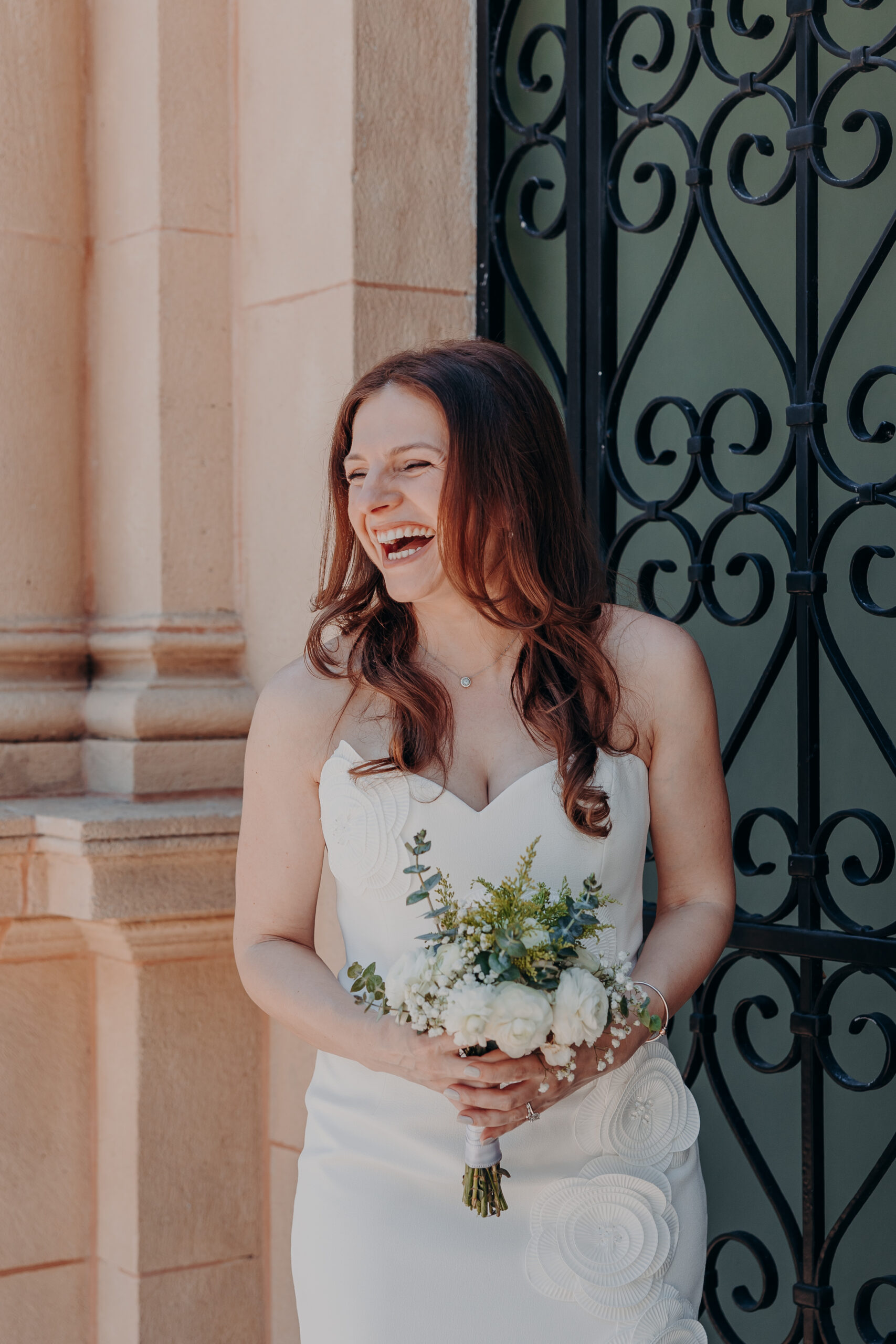 Bride Diana laughing in front of the ornate iron gates at the Historic Sarasota County Courthouse
