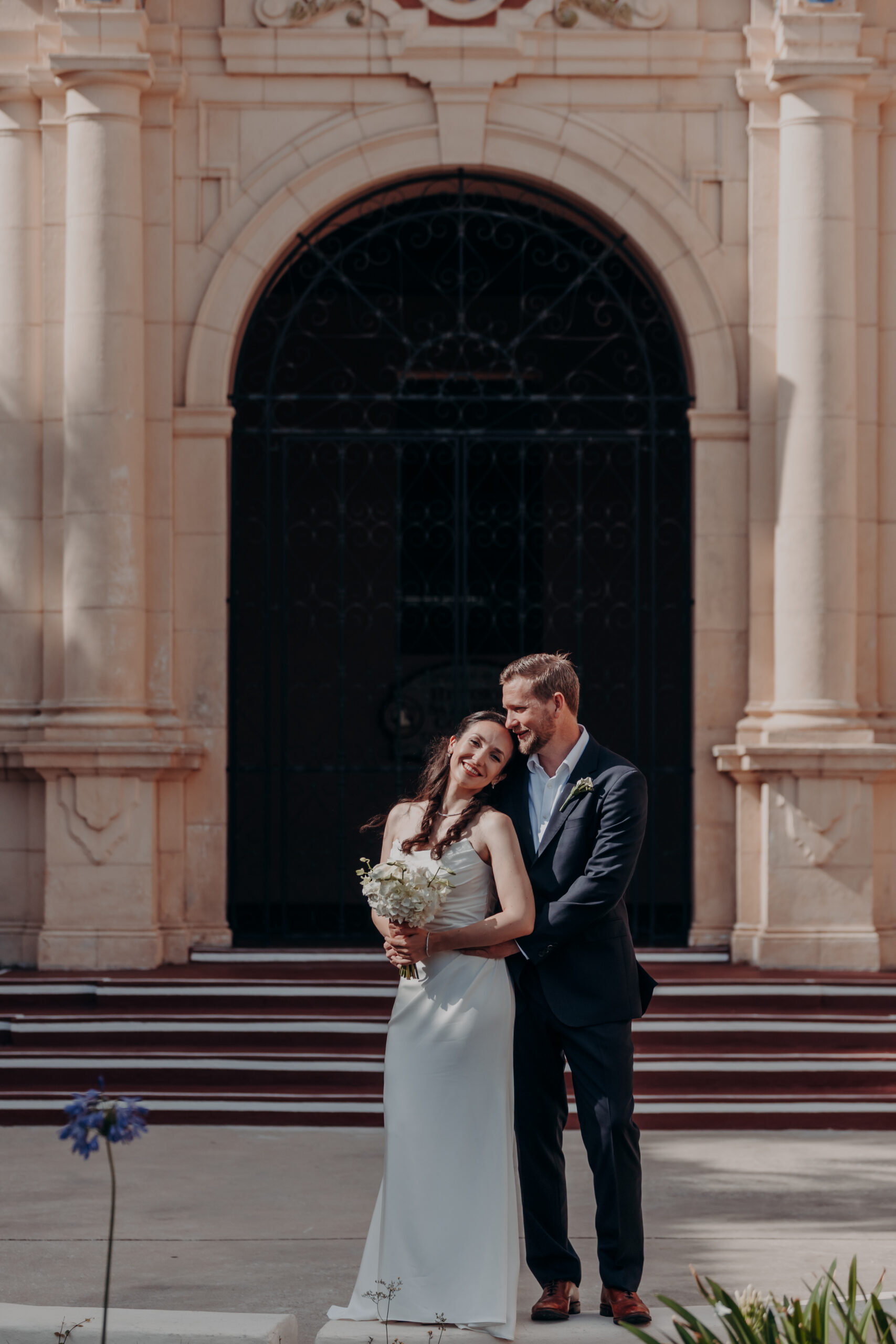 Liza laughing with her bouquet against the stone wall of the Sarasota courthouse
