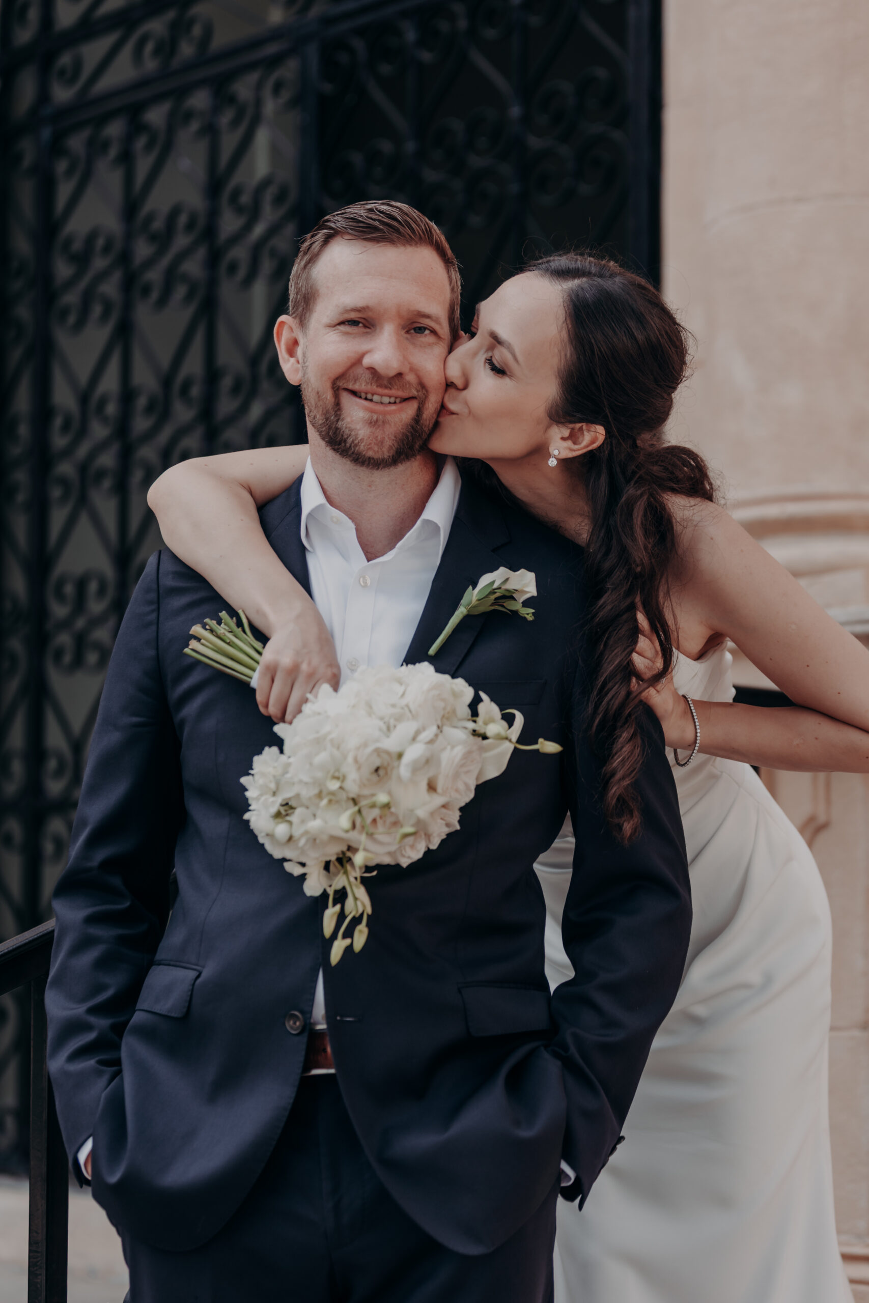 Liza and Will in a close embrace by the stone archway at the Historic Sarasota County Courthouse