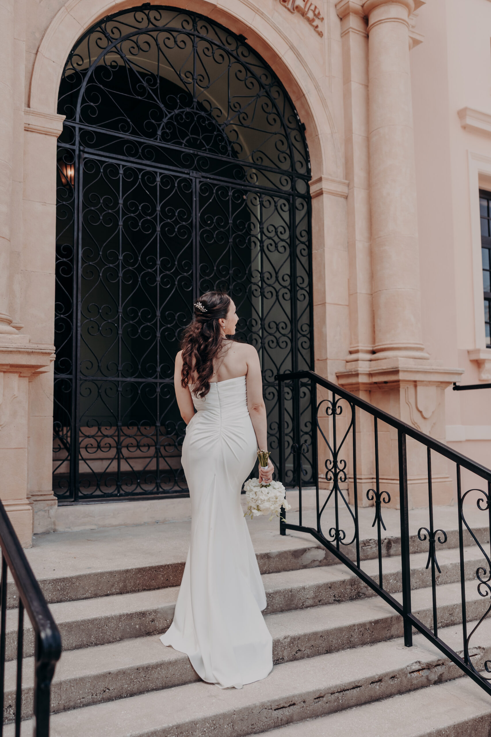 Liza and Will kissing at the Sarasota courthouse gate with Spanish colonial architecture in the background