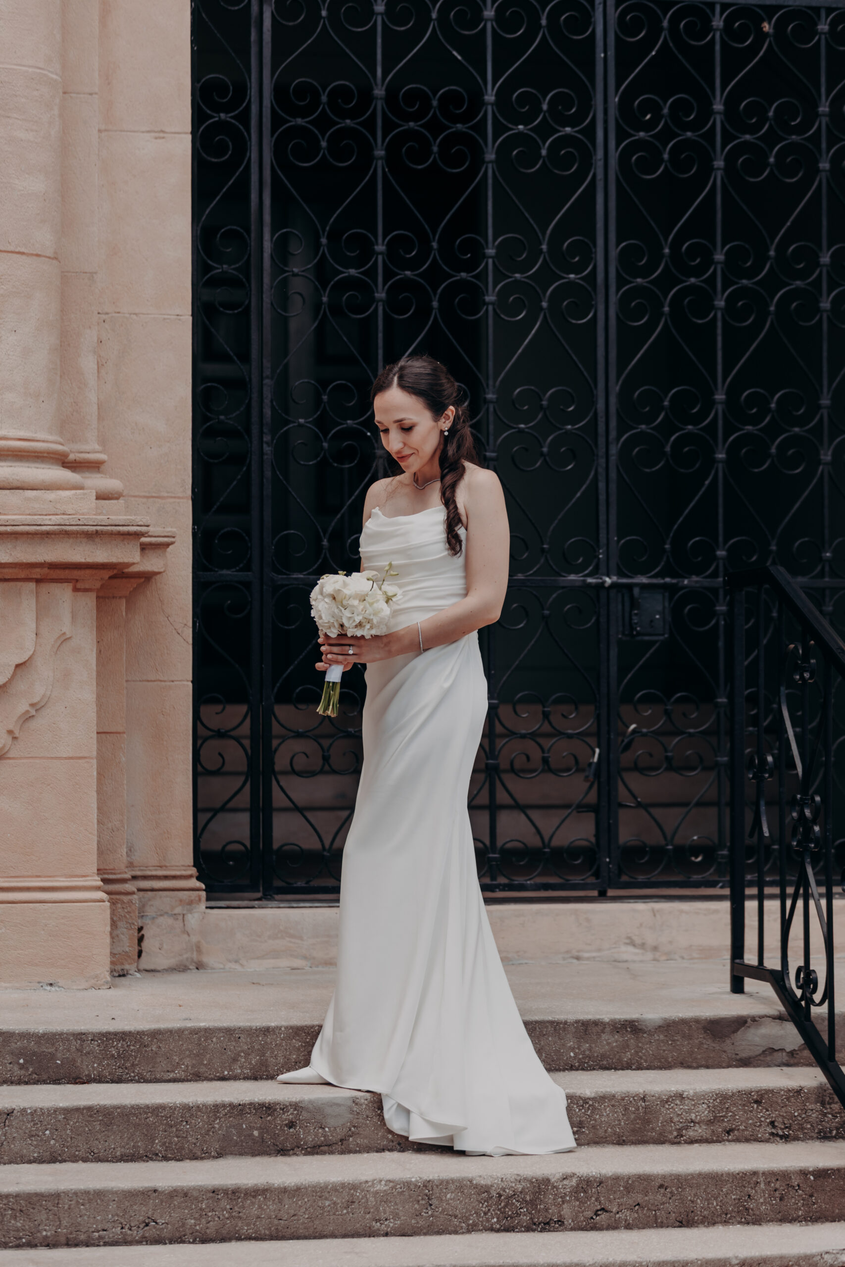 Liza holding her wedding flowers looking back at Will at the Sarasota Historic Courthouse