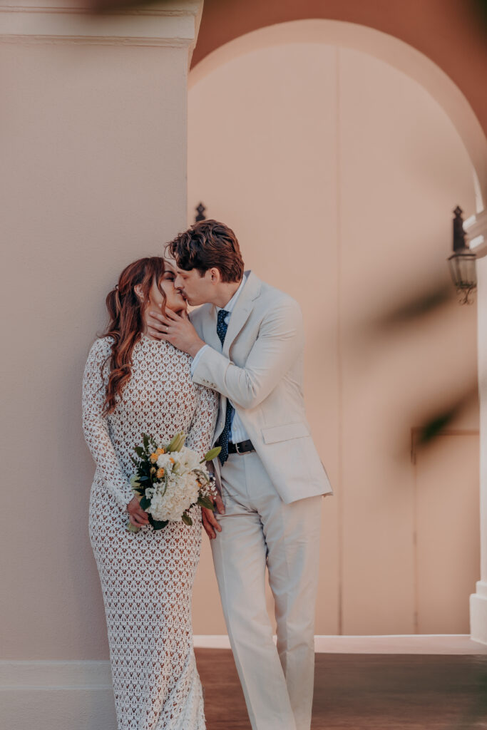 Wide shot of Mikaely and Chris kissing beneath the arched entrance of the Historic Sarasota County Courthouse during their Sarasota elopement