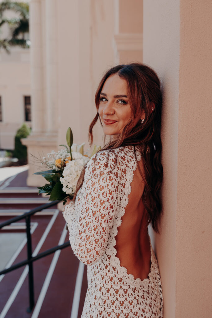 Close portrait of Mikaely smiling softly outdoors during her Sarasota courthouse elopement in her Anthropologie lace gown
