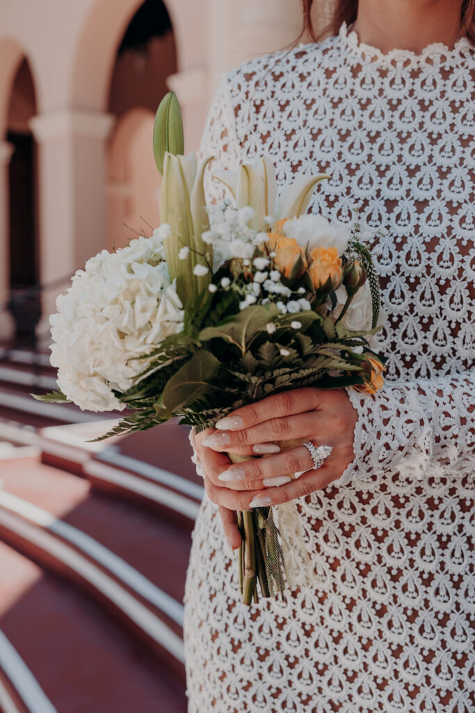 Close detail of Mikaelys white bouquet against her Anthropologie lace wedding gown at the Sarasota courthouse elopement