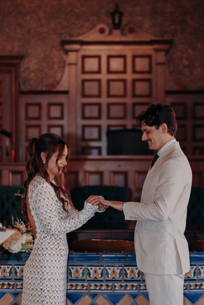Chris placing the wedding ring on Mikaelys hand during the ring exchange at the Historic Sarasota County Courthouse in Sarasota Florida