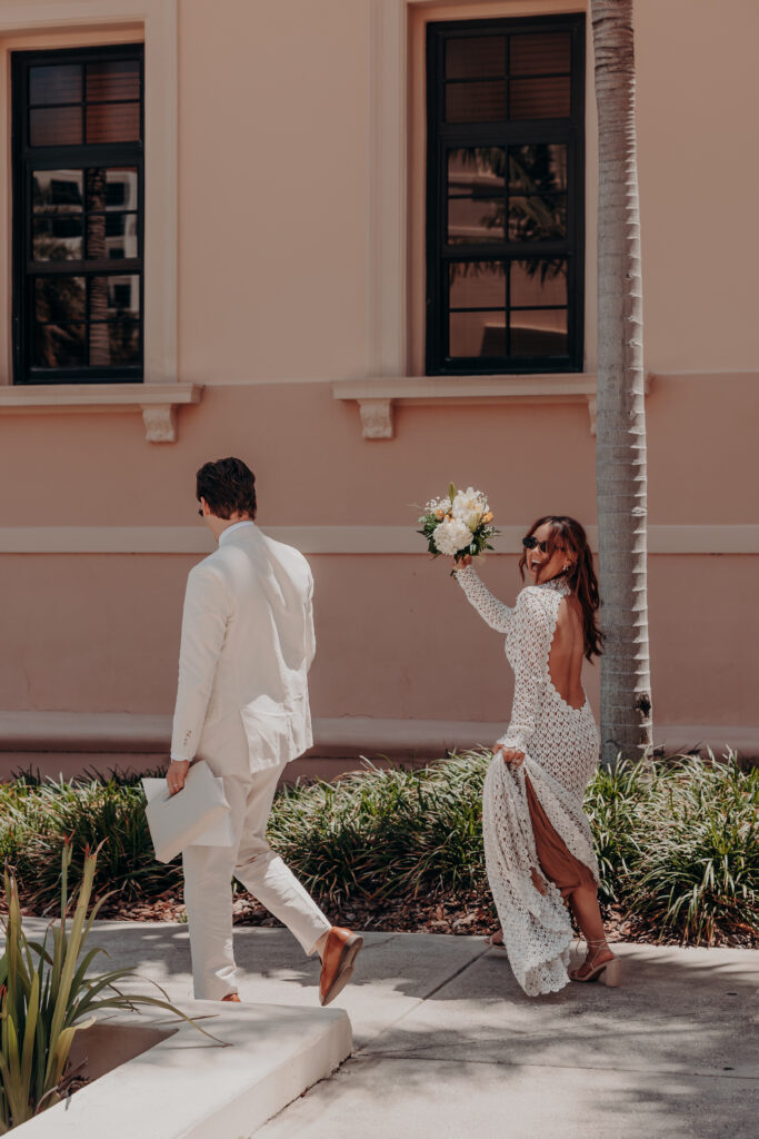 Mikaely and Chris beneath the exterior courthouse windows with a palm tree during their Sarasota Florida courthouse elopement