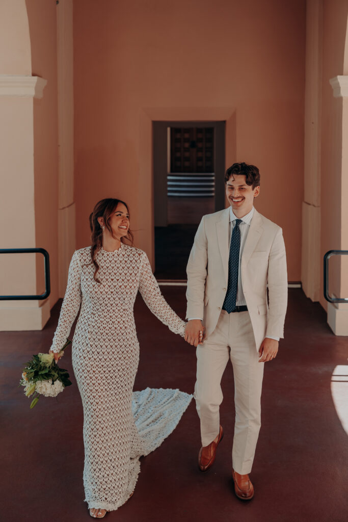Mikaely and Chris walking and laughing together beneath the arched exterior entrance of the Historic Sarasota County Courthouse in Sarasota FL