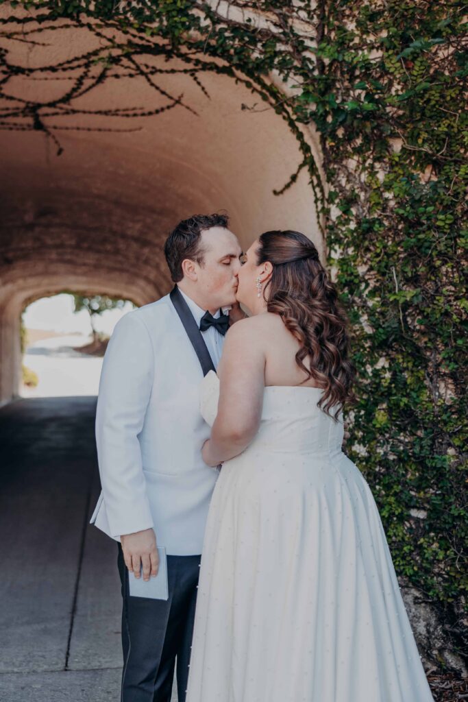 Bride and groom kissing under ivy archway tunnel at Lakewood Ranch Golf and Country Club