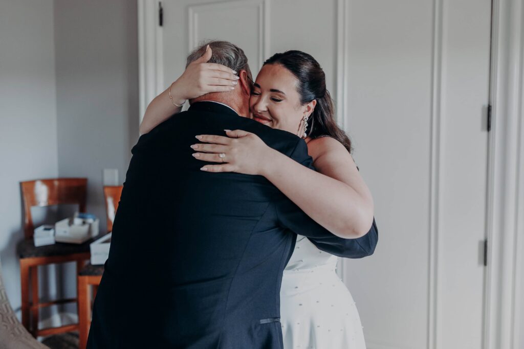 Bride hugging her father in emotional first look moment smiling over his shoulder