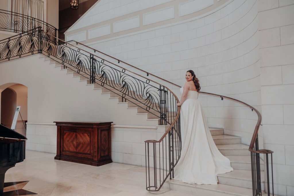 Bride in pearl gown on grand staircase at Lakewood Ranch Golf and Country Club with ornate iron railing