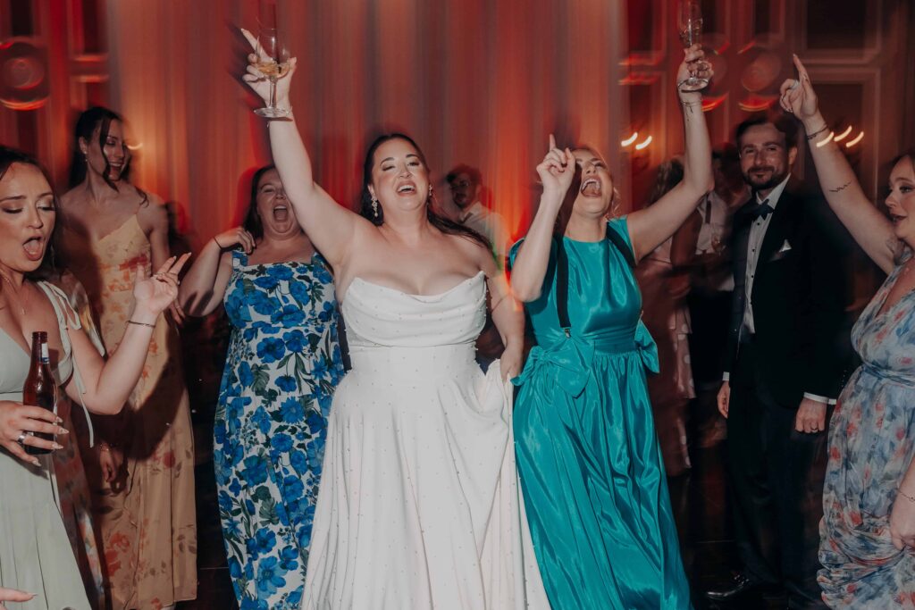 Bride with arms raised holding champagne on packed dance floor at Lakewood Ranch Golf and Country Club reception