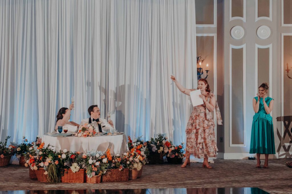 Bridesmaid giving toast while couple raises glasses at sweetheart table at Lakewood Ranch wedding reception