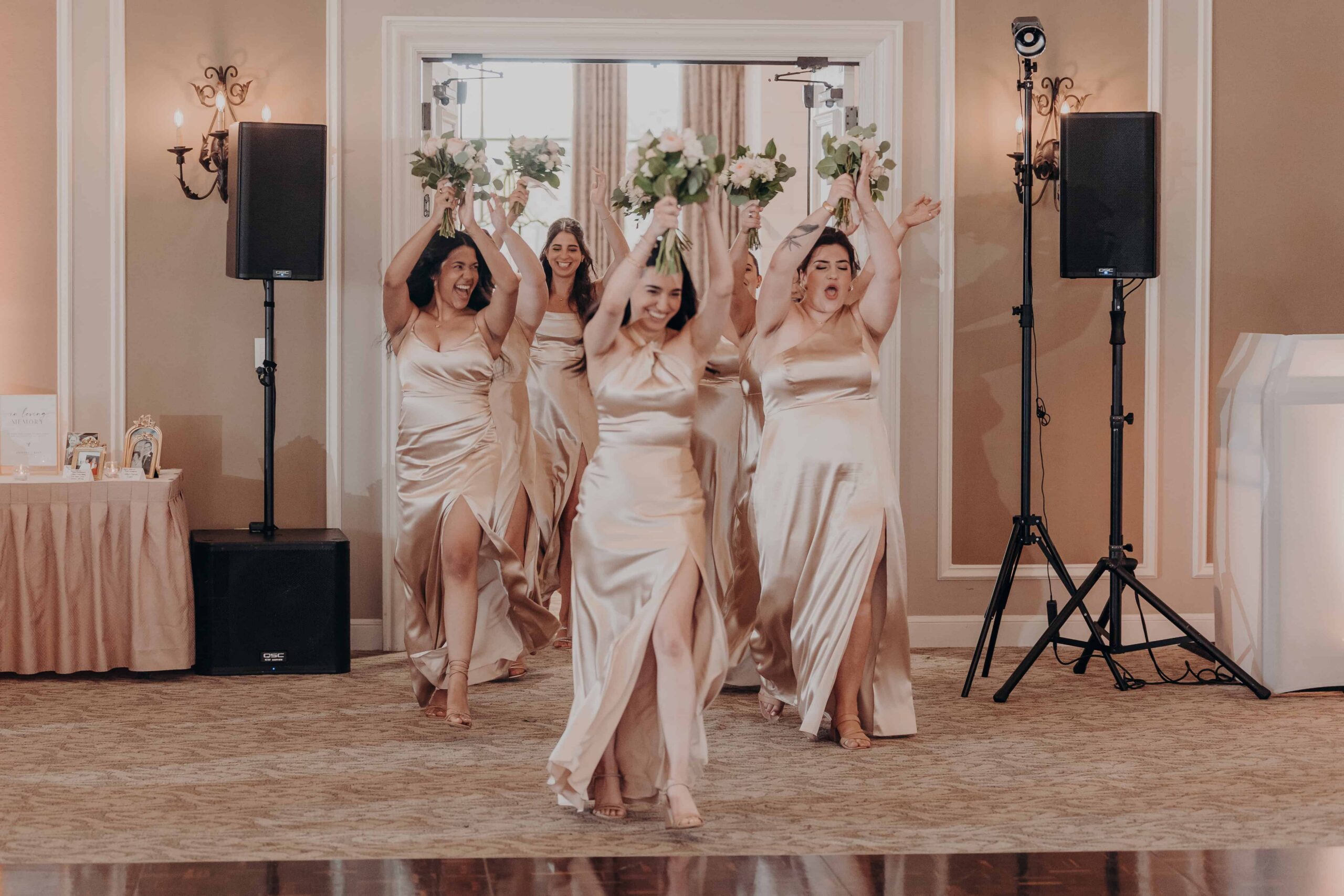 Bridesmaids making grand entrance with bouquets raised over their heads at Lakewood Ranch Golf and Country Club wedding reception