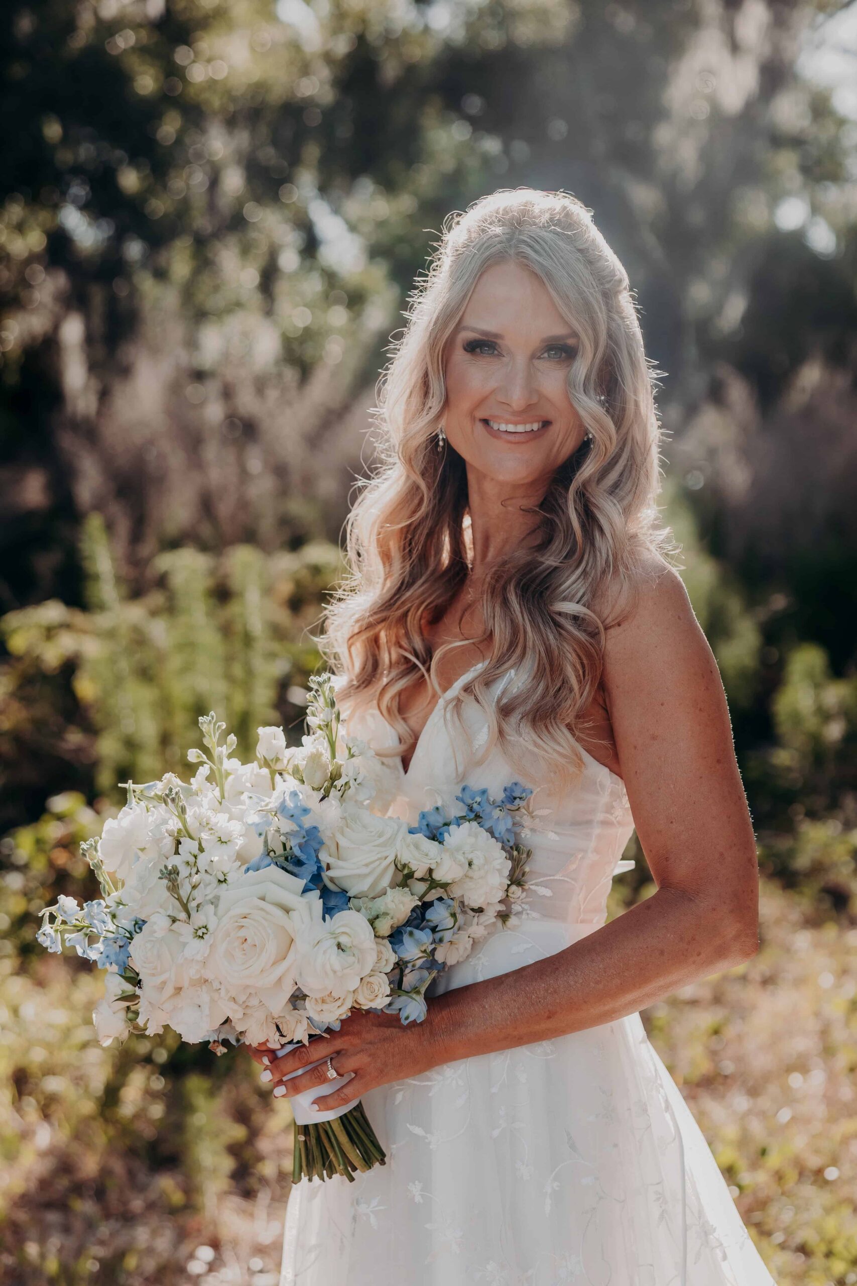 Bridal portrait with white rose and blue delphinium bouquet under Spanish moss at Brown's Grove Farm