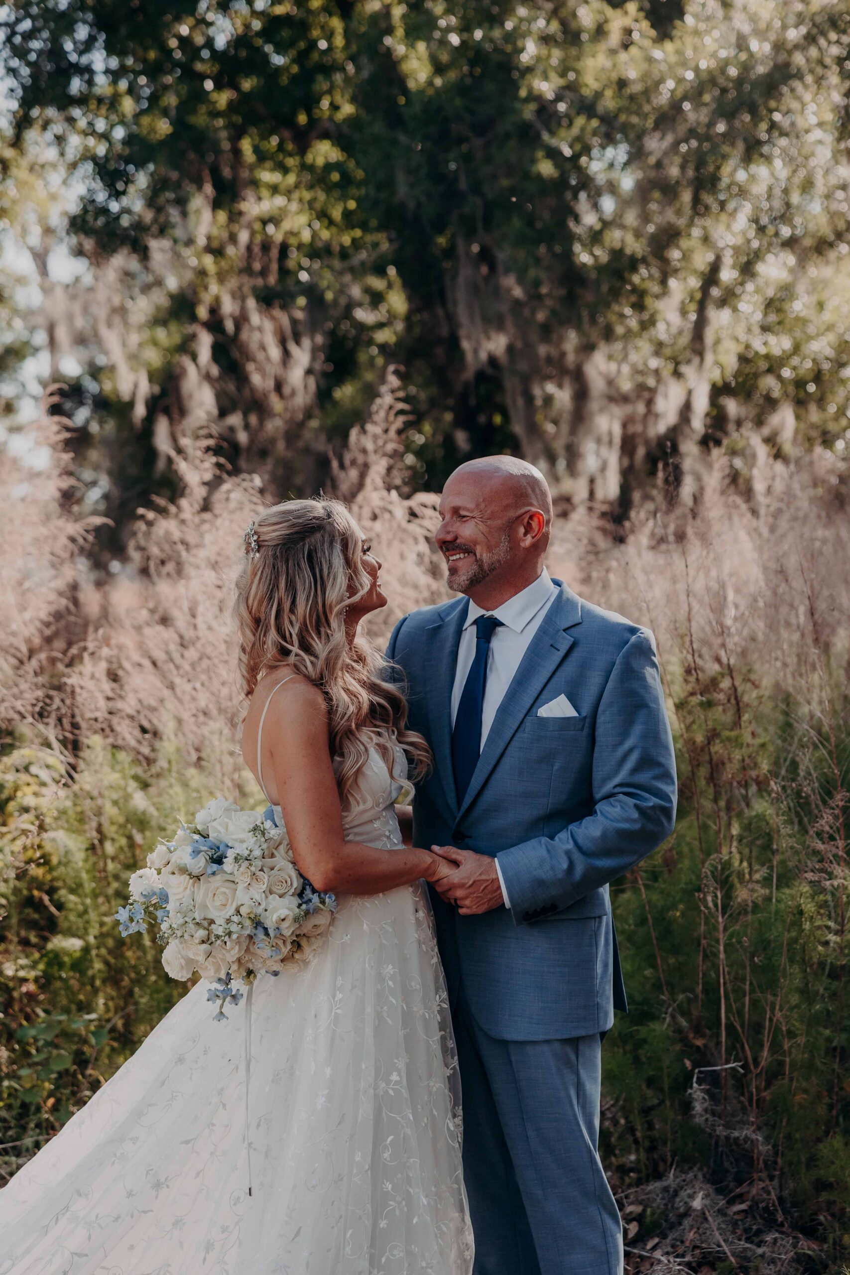 Couple romantic moment in pampas grass under Spanish moss oak trees at Brown's Grove Farm wedding
