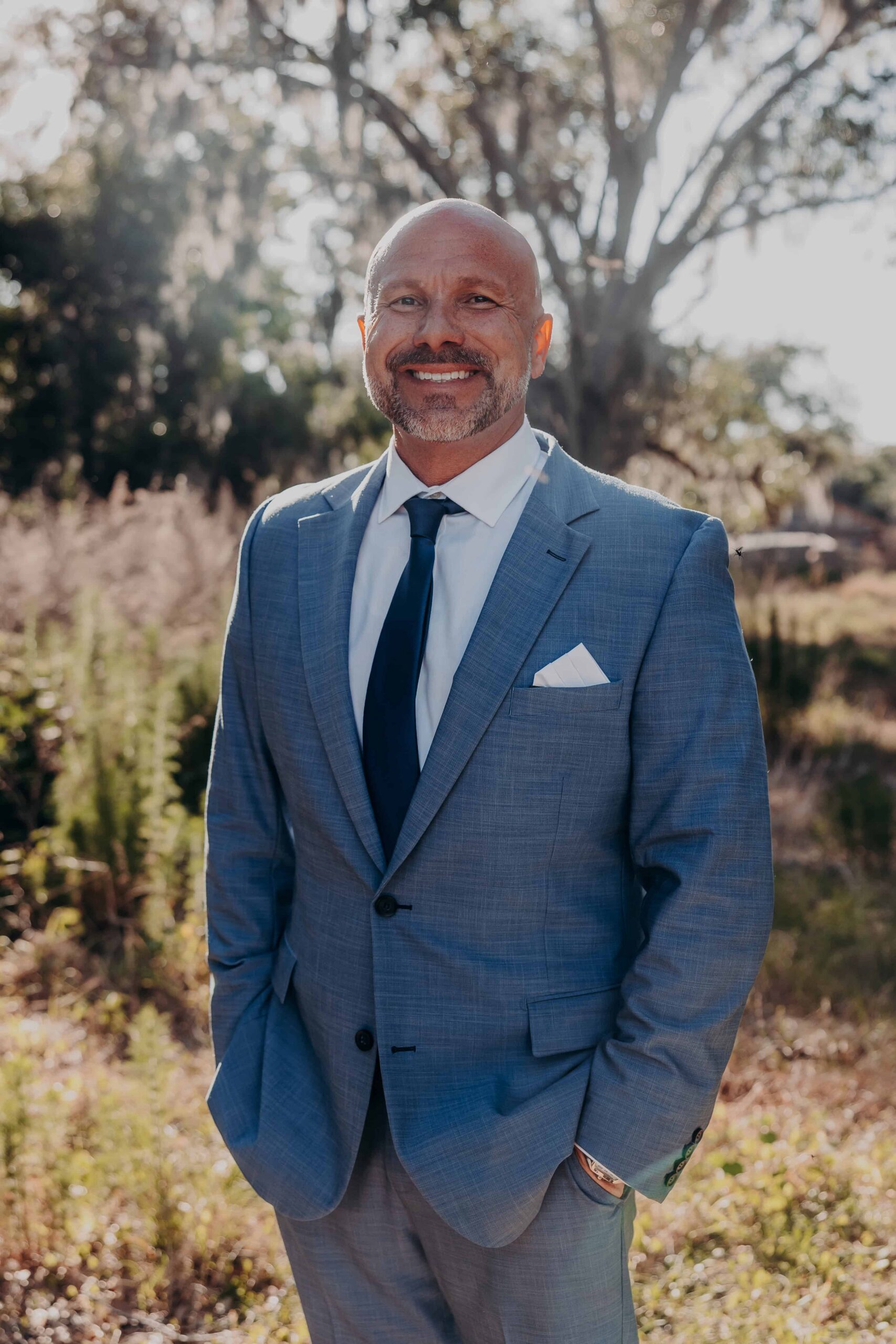 Groom Josh portrait in blue suit under oak tree at Brown's Grove Farm wedding Parrish Florida
