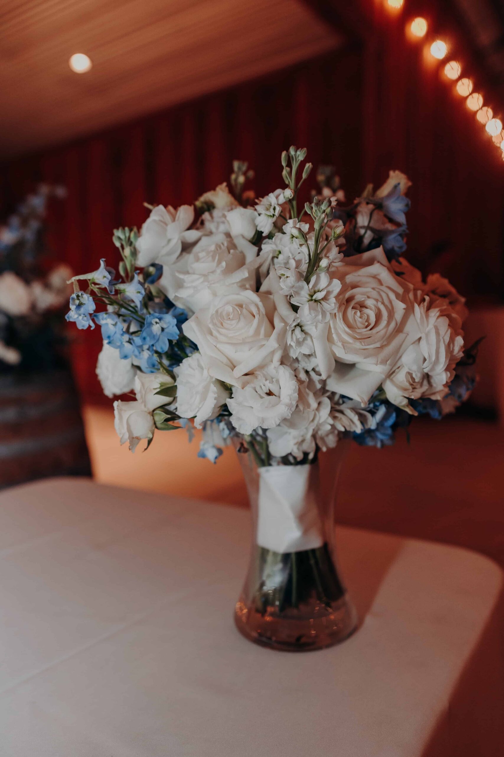 White rose and blue delphinium bridal bouquet detail at Brown's Grove Farm wedding reception