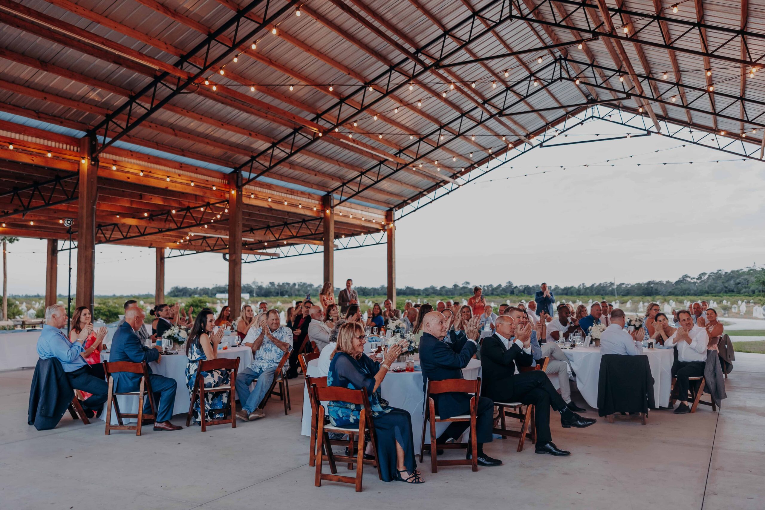 Wide pavilion shot with all wedding guests applauding at Brown's Grove Farm reception