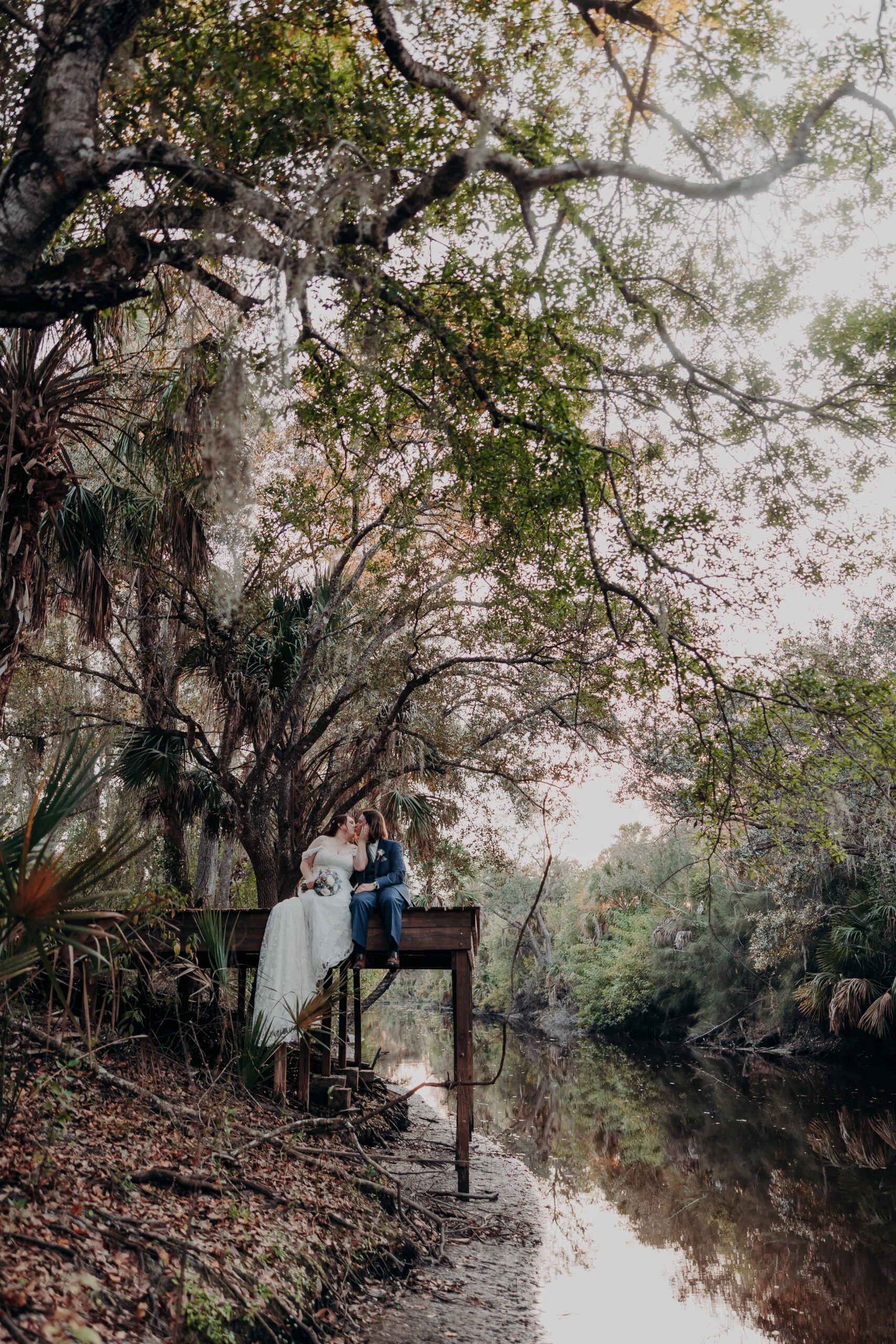 Bride and groom kissing while sitting on a dock over the river at Chapel Creek Ranch Parrish Florida