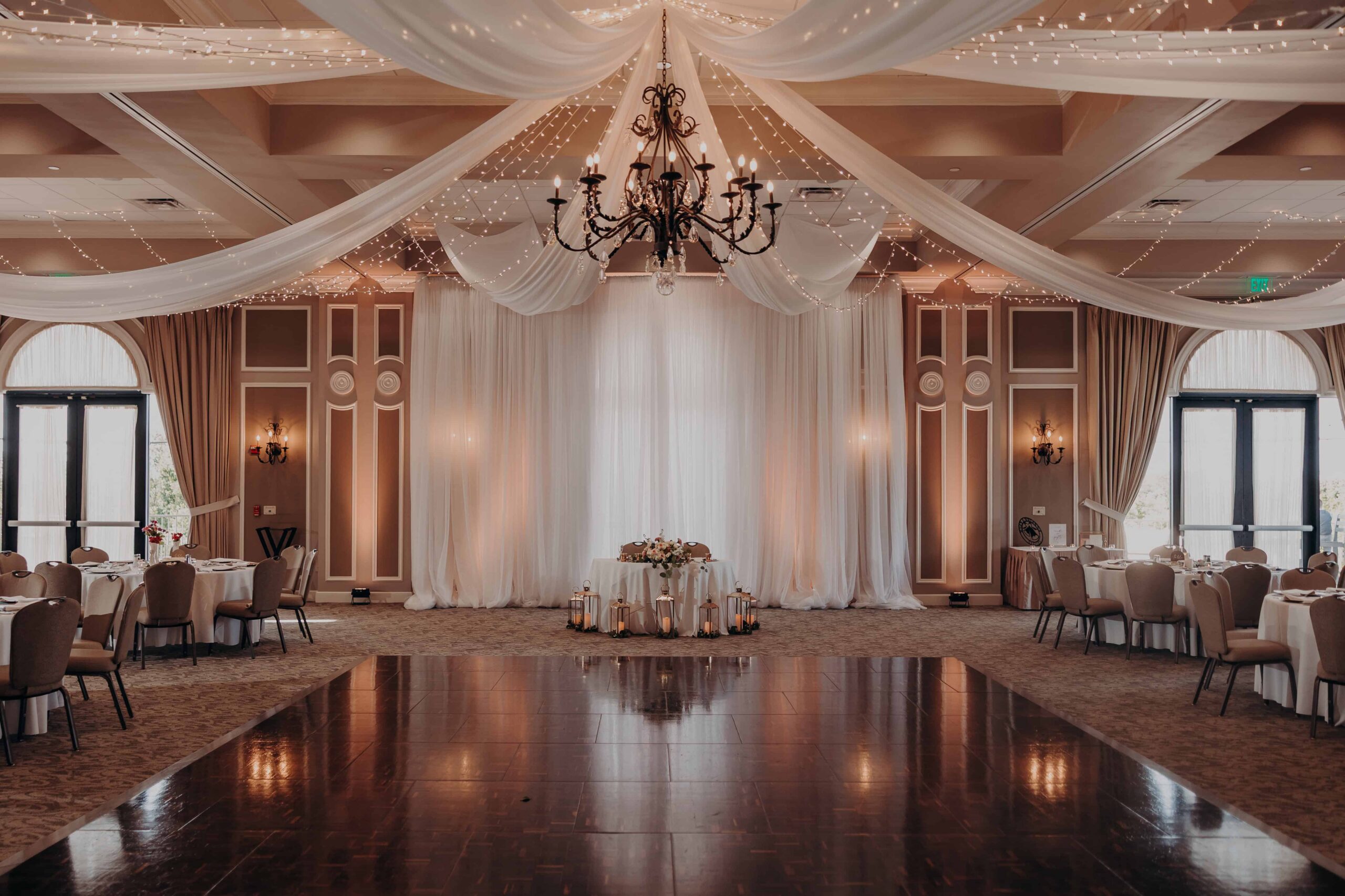 Colorful floral centerpieces in sculptural white vases with gold charger plates by Blossoms and Bubbly at Lakewood Ranch Golf and Country Club reception