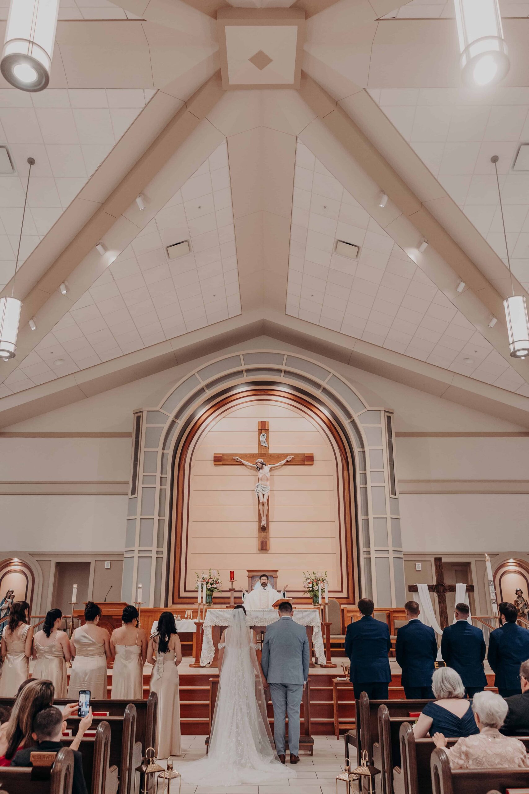 First kiss at the altar of Our Lady of the Angels Catholic Church in Lakewood Ranch Florida with crucifix behind Brianna and Ryan Whitley