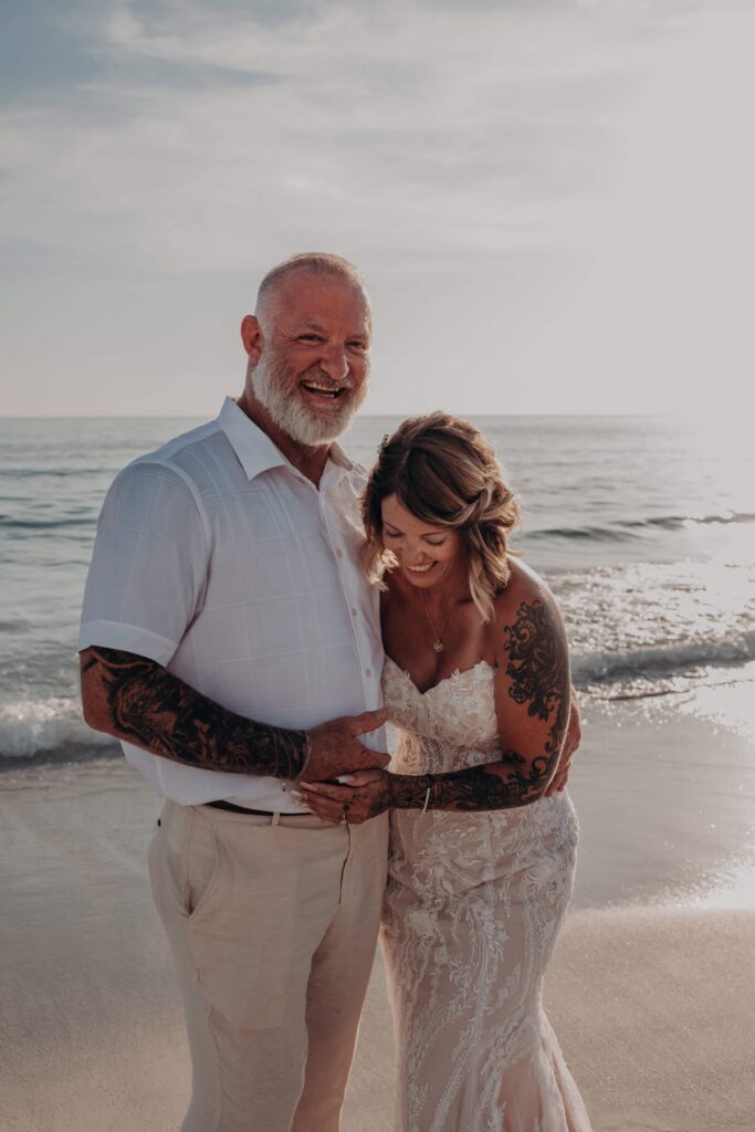 Golden pink sky at sunset behind newlyweds Sarah and Jasen on Siesta Key beach