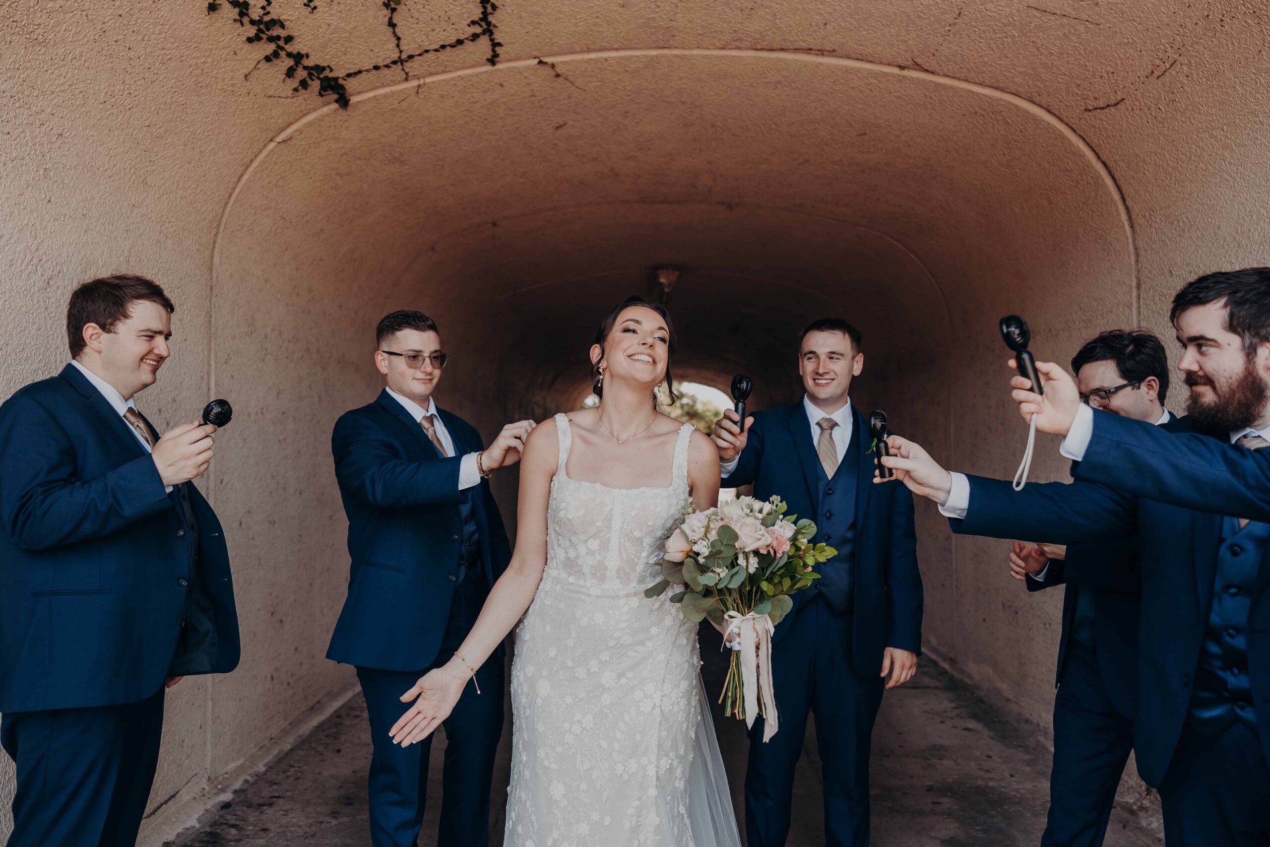 Groomsmen pretending to interview bride Brianna with microphone props in the ivy tunnel at Lakewood Ranch Golf and Country Club