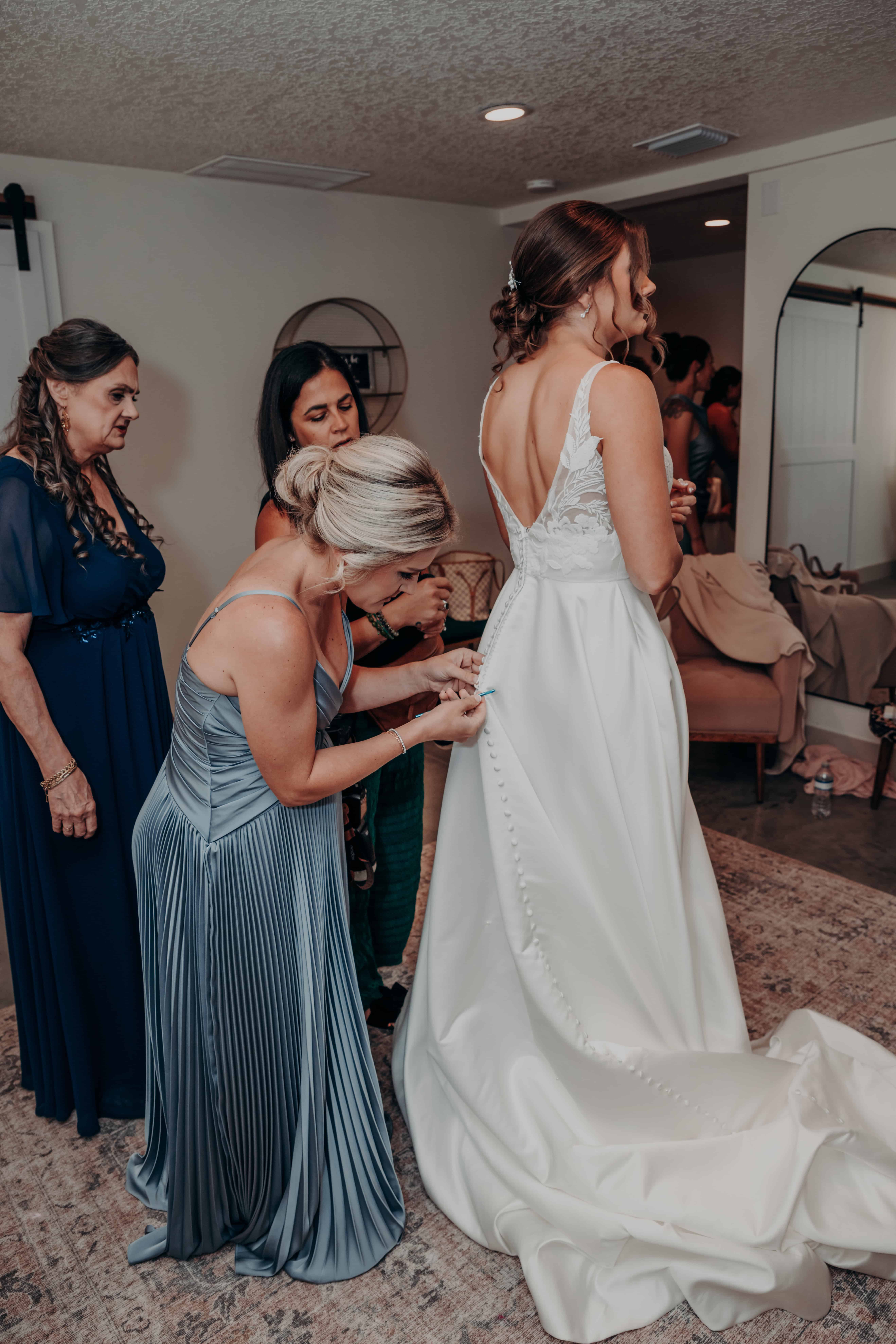 Hidden Acres wedding bride getting dressed buttons back of dress