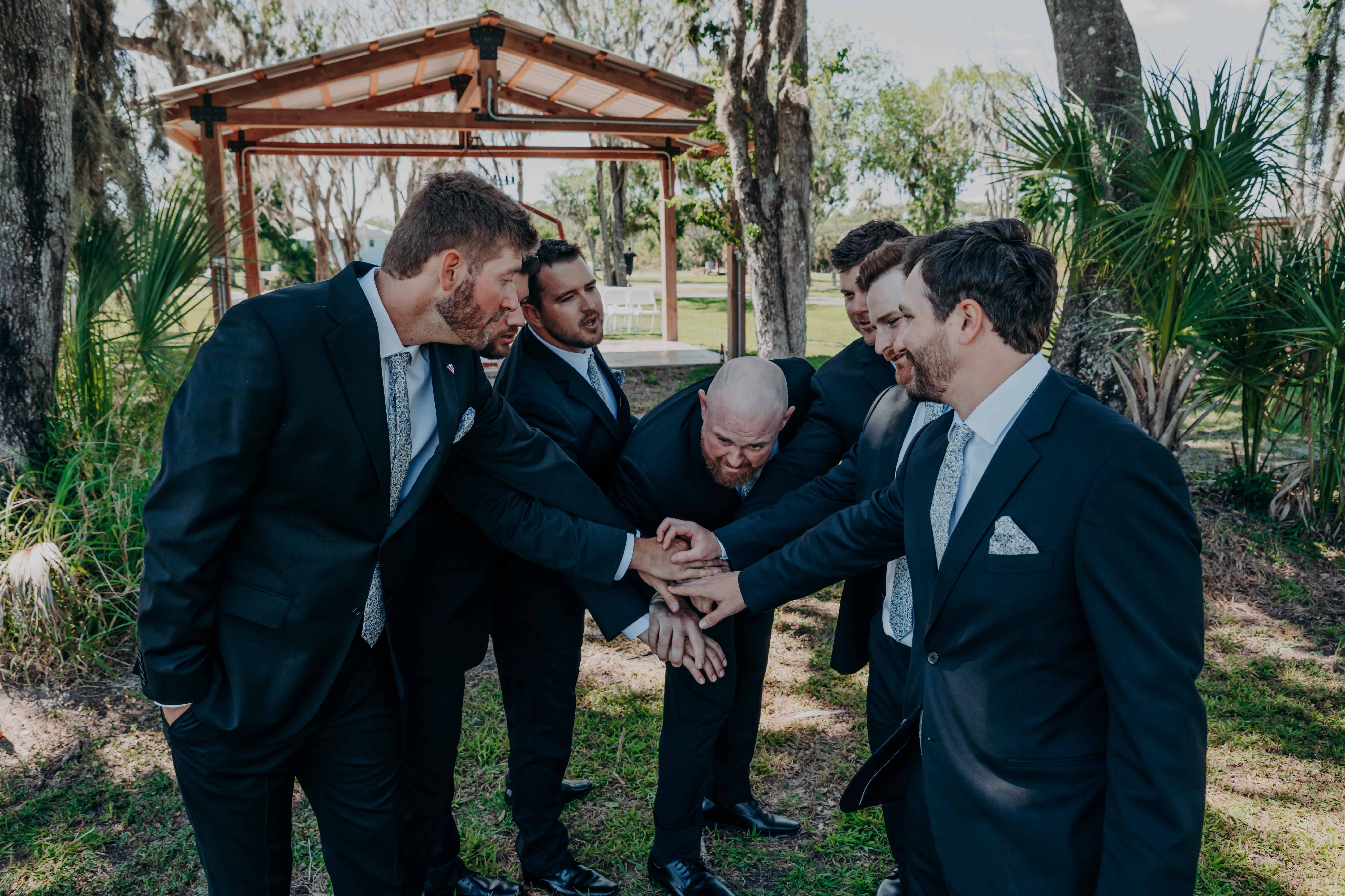 Hidden Acres wedding groomsmen hands in huddle