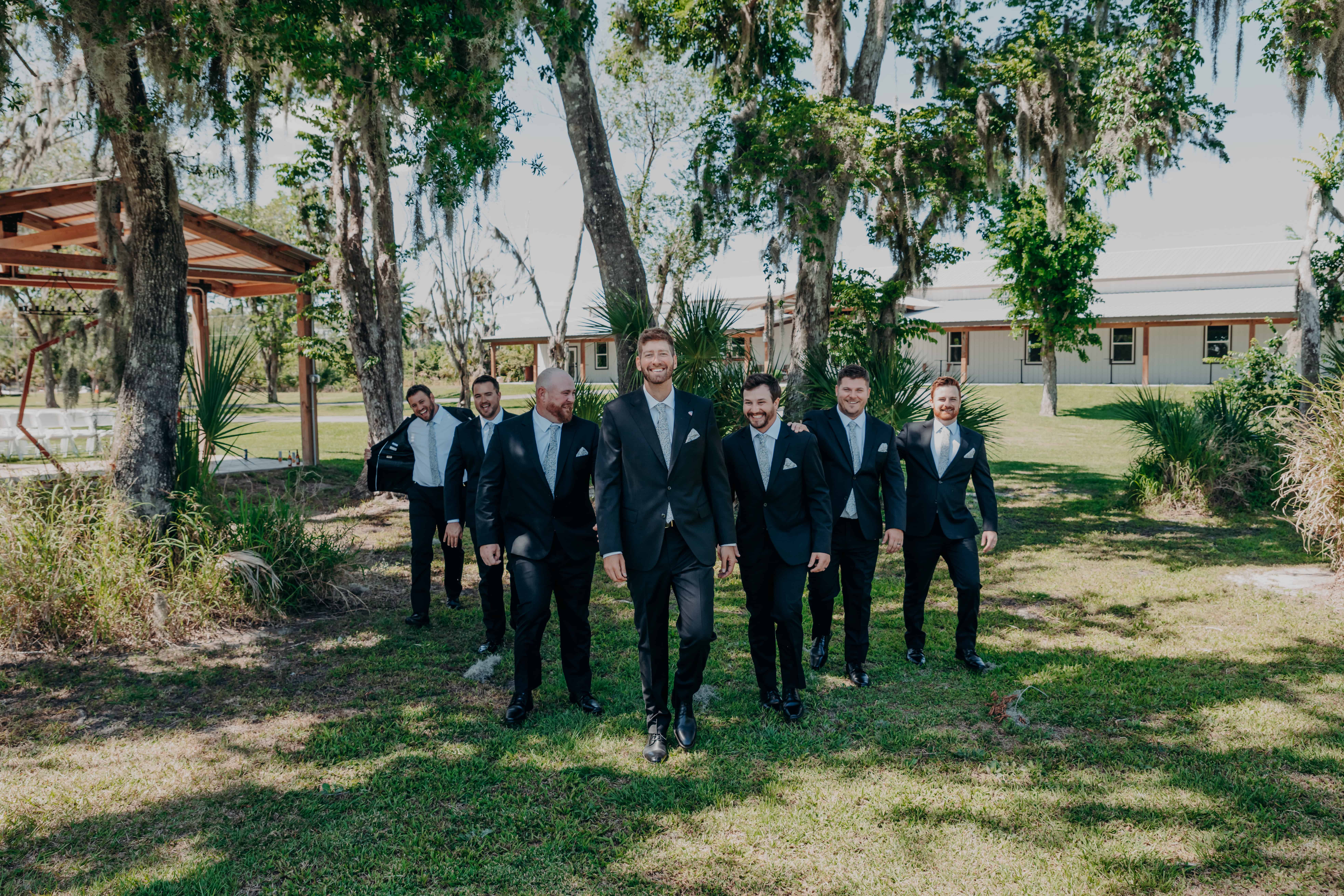 Hidden Acres wedding groomsmen walking through Spanish moss trees