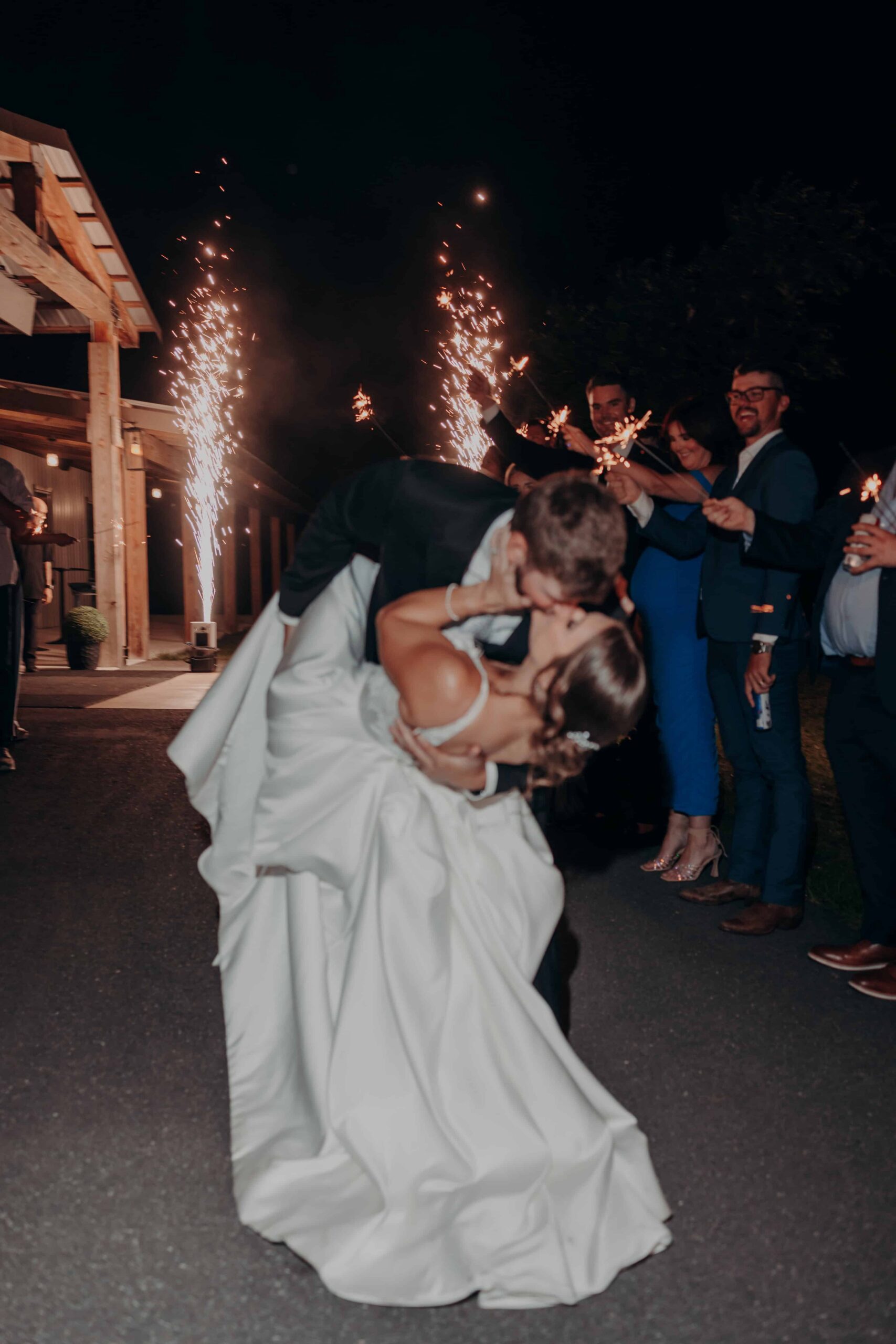 Hidden Acres wedding sparkler exit dip kiss at night with guests