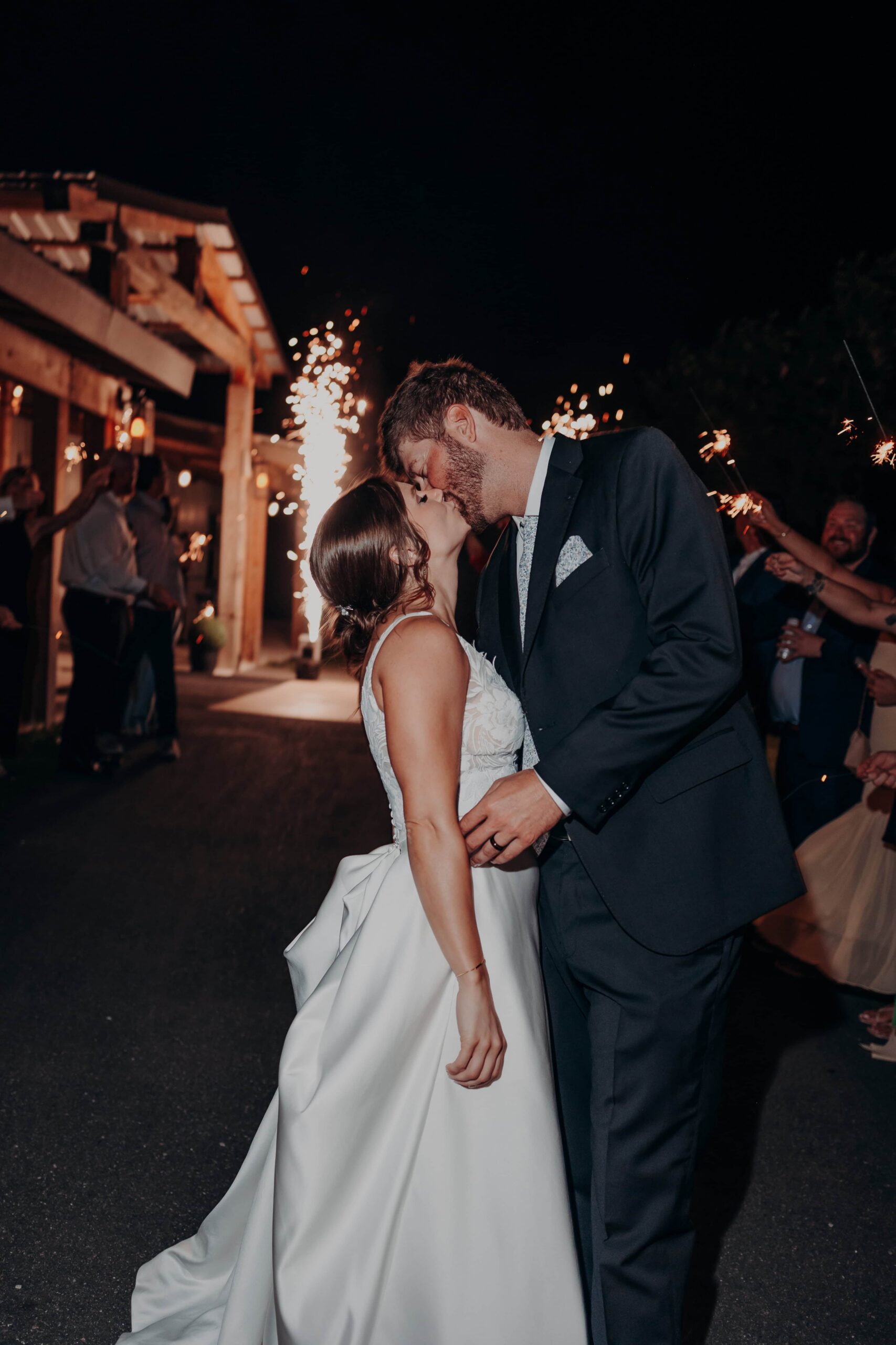 Hidden Acres wedding sparkler exit kiss at night in front of venue