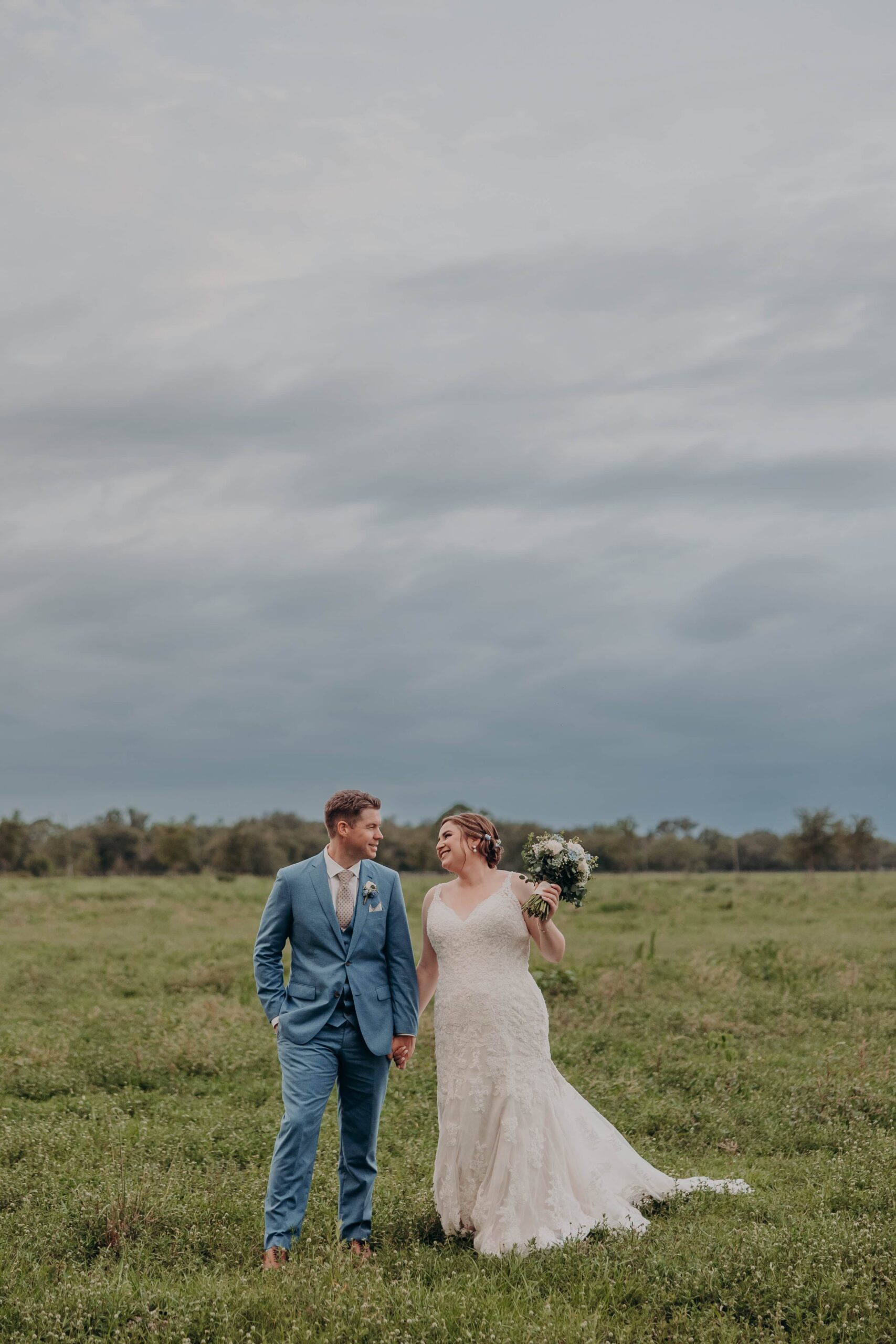 Couple standing in open green pasture with dramatic cloudy sky at Hudson Manor Myakka City Florida