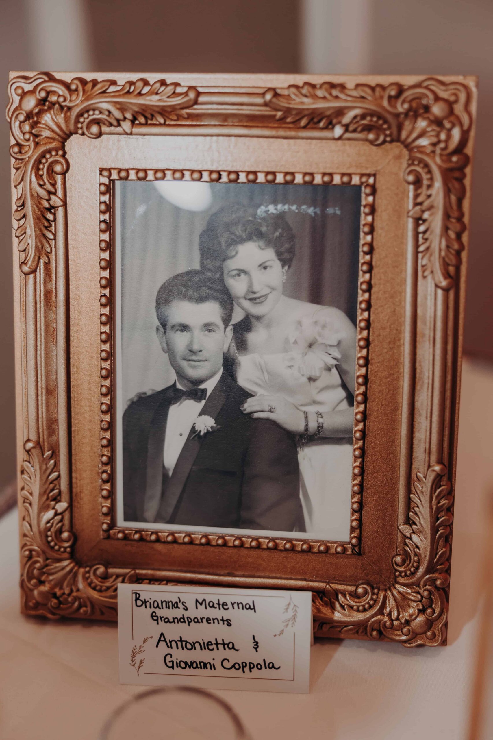 Memory table with framed family photos including vintage portrait of Brianna grandparents at Lakewood Ranch Golf and Country Club wedding reception
