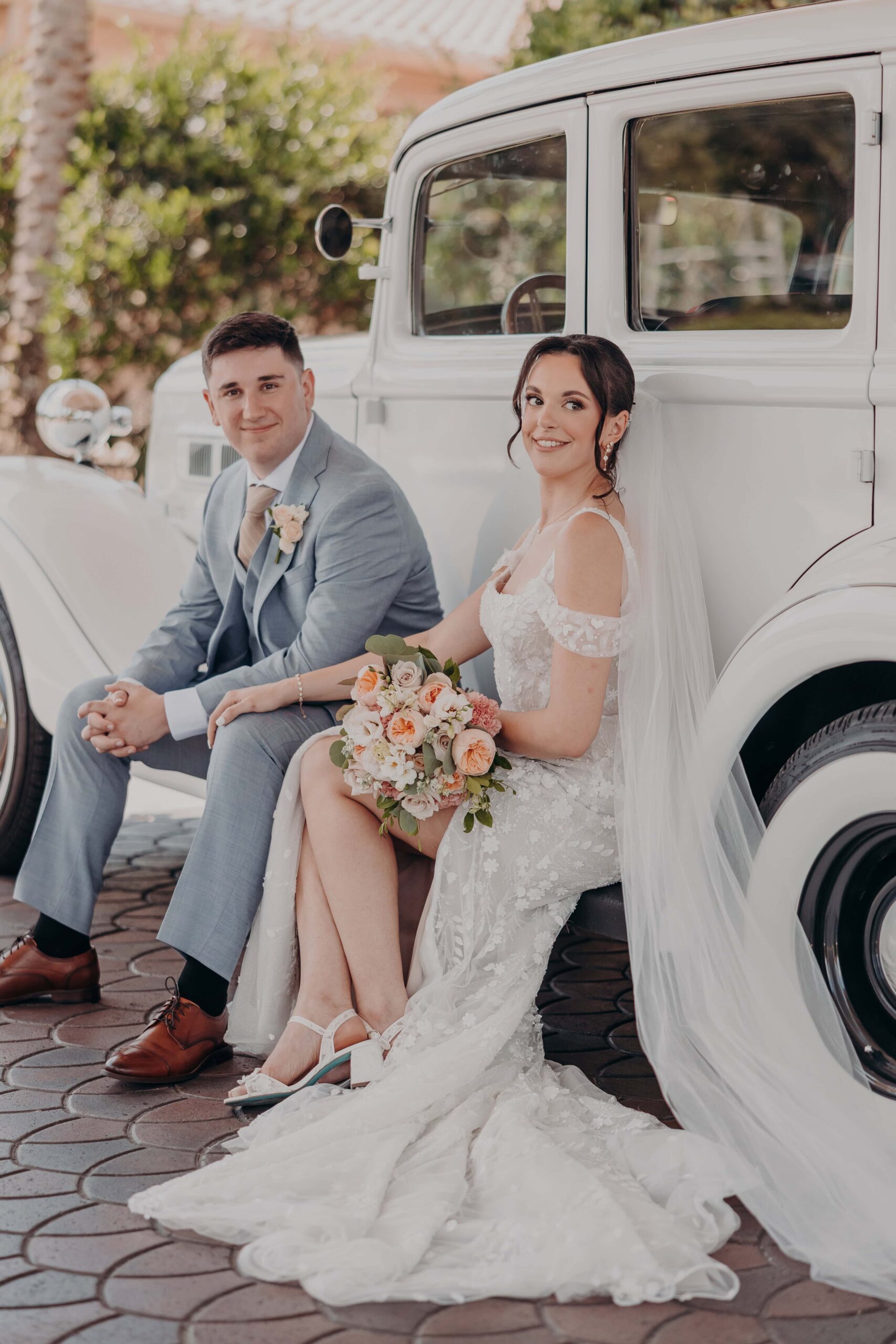 Newlyweds Brianna and Ryan with vintage white classic car on cobblestone at Lakewood Ranch Golf and Country Club after their Our Lady of the Angels ceremony