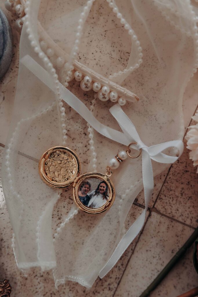 Open gold locket with photo of bride and her mother beside pearl hair clip on wedding morning