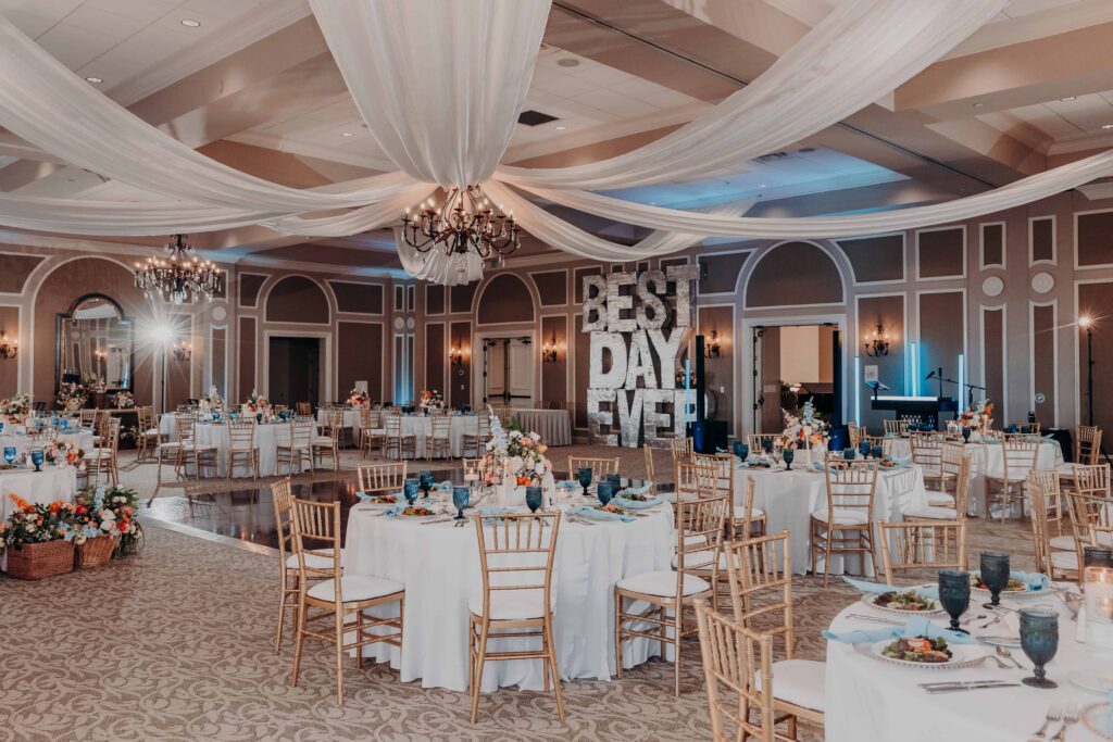 Reception ballroom at Lakewood Ranch Golf and Country Club with BEST DAY EVER marquee blue goblets and chandeliers