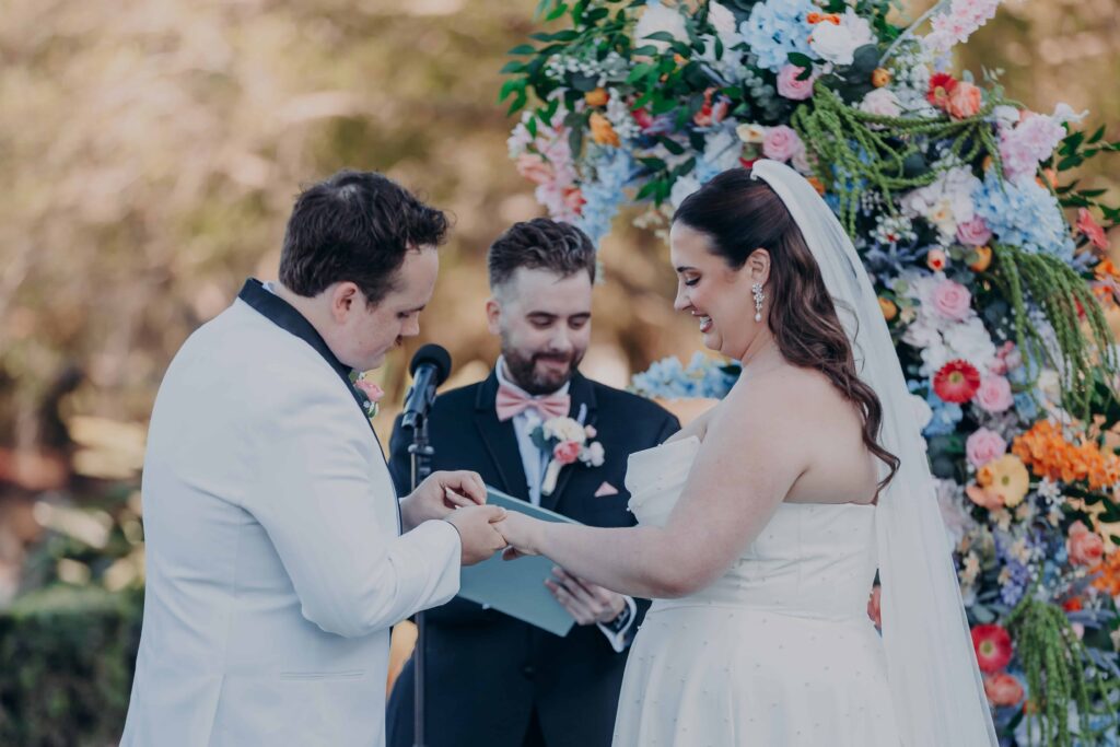 Ring exchange at Lakewood Ranch Golf and Country Club ceremony with stunning colorful floral arch