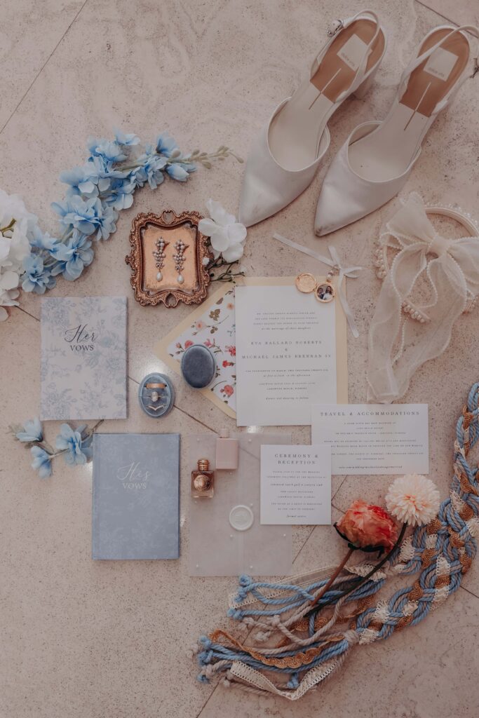 Wedding invitation flatlay with dusty blue vow books pearl earrings and hydrangeas - Lakewood Ranch Golf and Country Club wedding