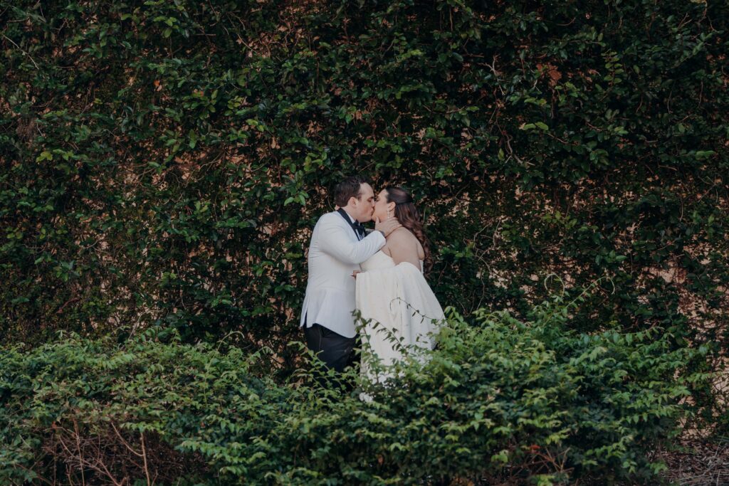 Wide editorial shot of couple kissing against full ivy wall at Lakewood Ranch Golf and Country Club