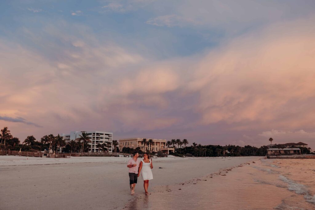 siesta key beach proposal couple walking champagne cotton candy sky sarasota