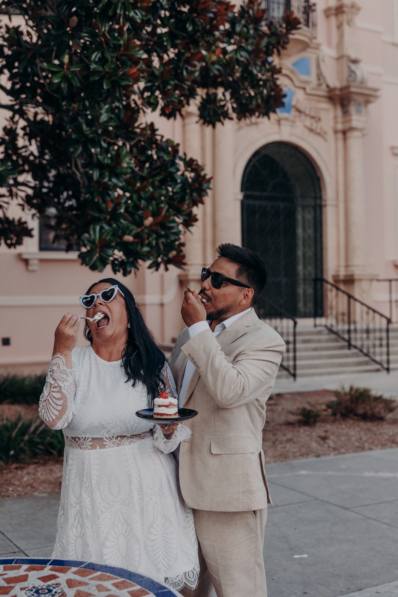 Karlee and Caleb laughing while feeding each other cake outside the courthouse